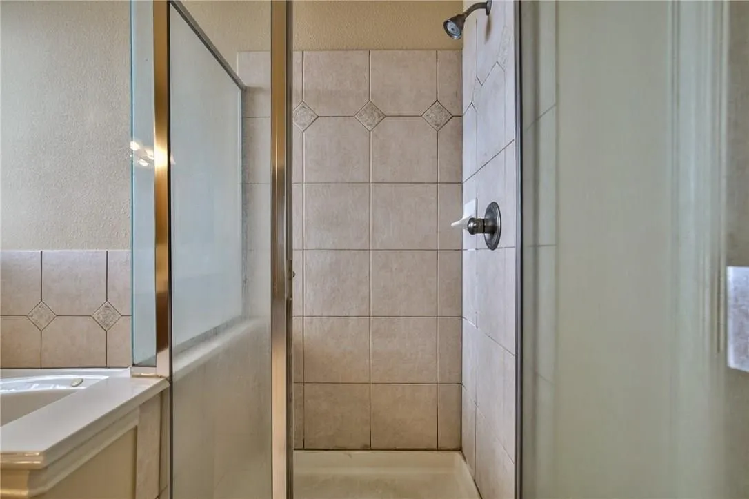 Tiled shower enclosure featuring a dark bronze shower head and coordinating fixtures