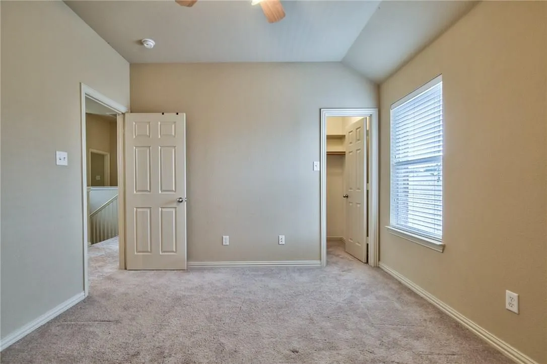 Carpeted room with vaulted ceilings and a ceiling fan