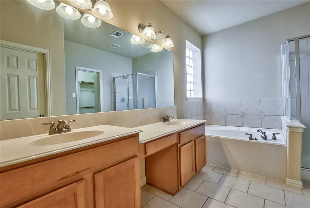 Dual vanity with undermount sinks, wood cabinetry, and a full-width mirror