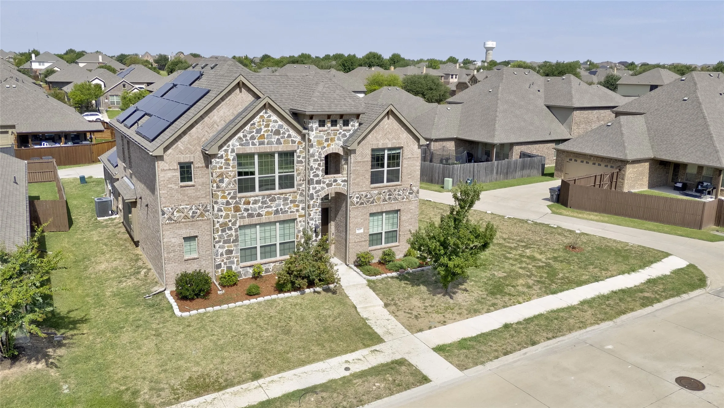 Two-story brick and stone front elevation in Harmony, Red Oak TX, with arched entry and solar panels