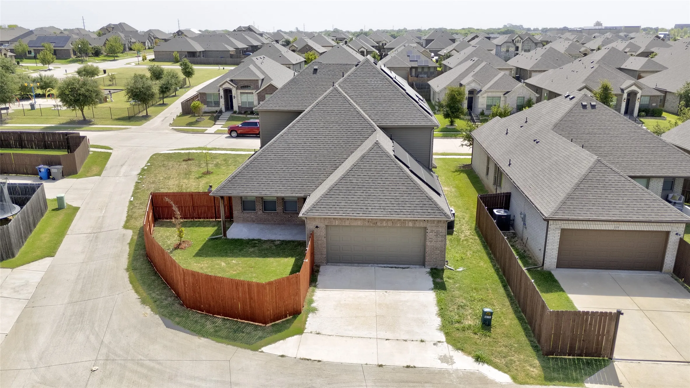 Rear view of the two-car garage, driveway, and fenced yard with covered patio on this corner lot