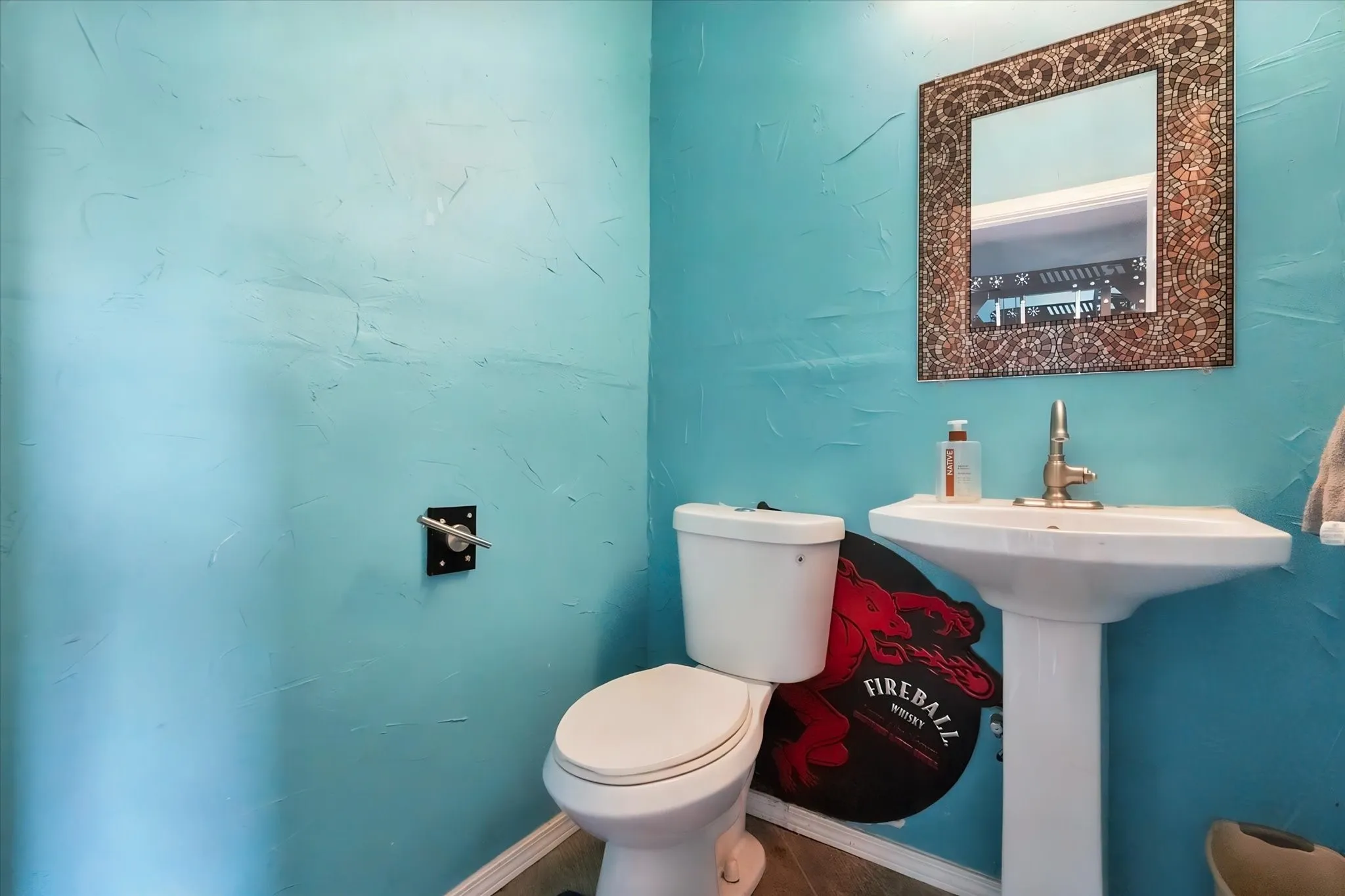 Half Bath conveniently located in the workshop. Textured wall finish, pedestal sink, wall-mounted mirror with decorative frame, white toilet, and tile flooring