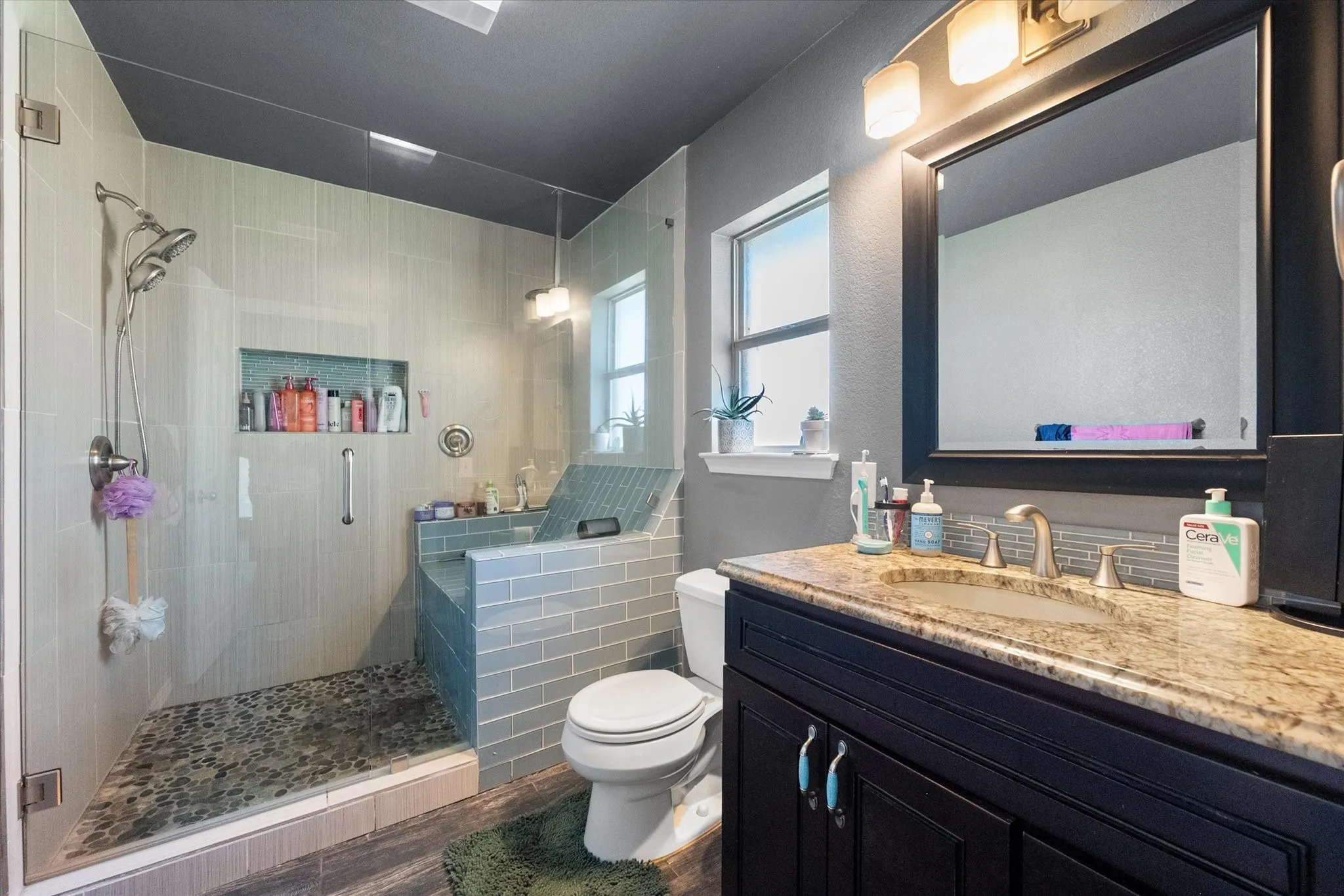 Glass-enclosed shower with a built-in bench, tiled shower niche, and a dual-head shower system