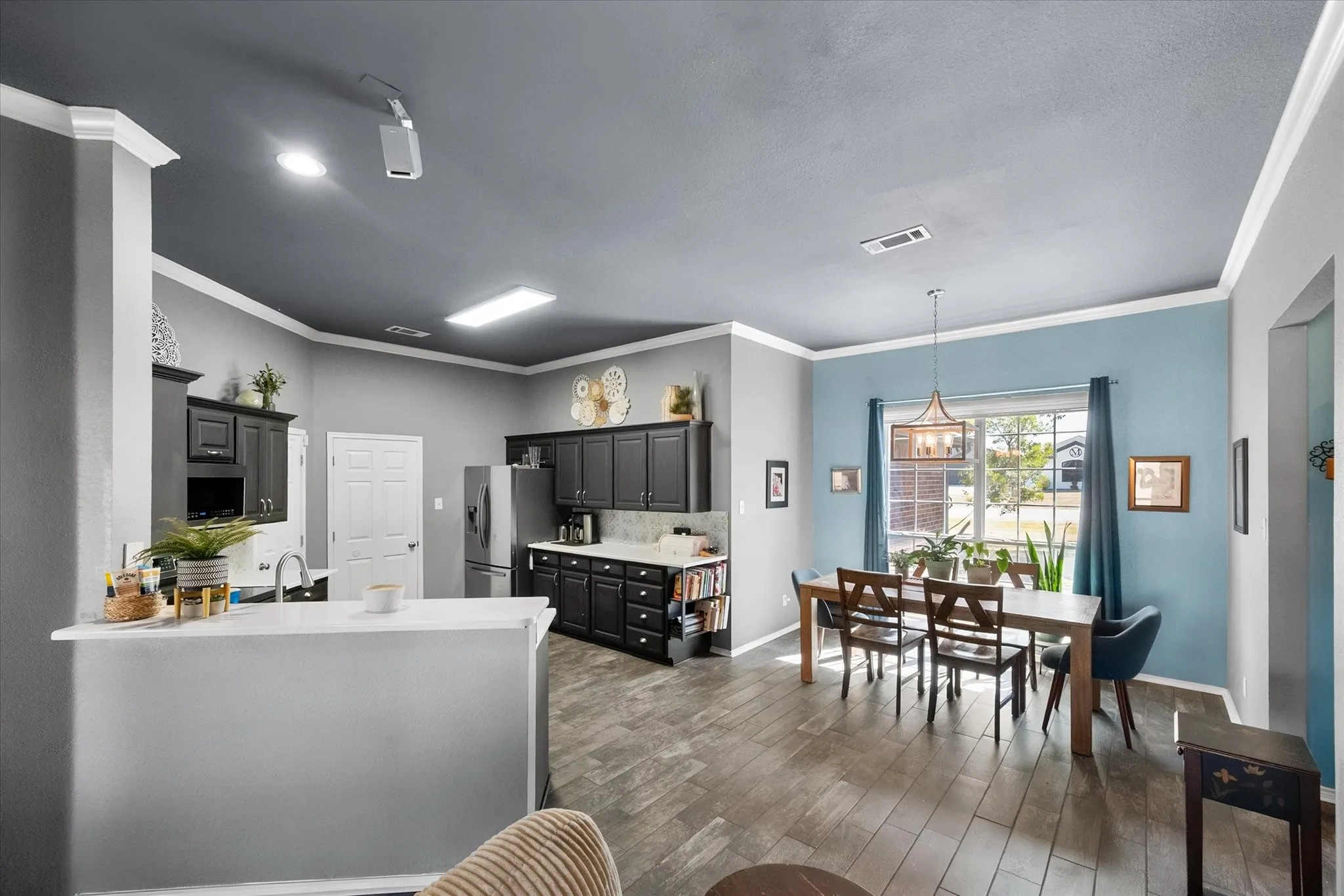 Spacious kitchen featuring dark cabinetry and a breakfast bar, opening to a dining area with wood-finish flooring