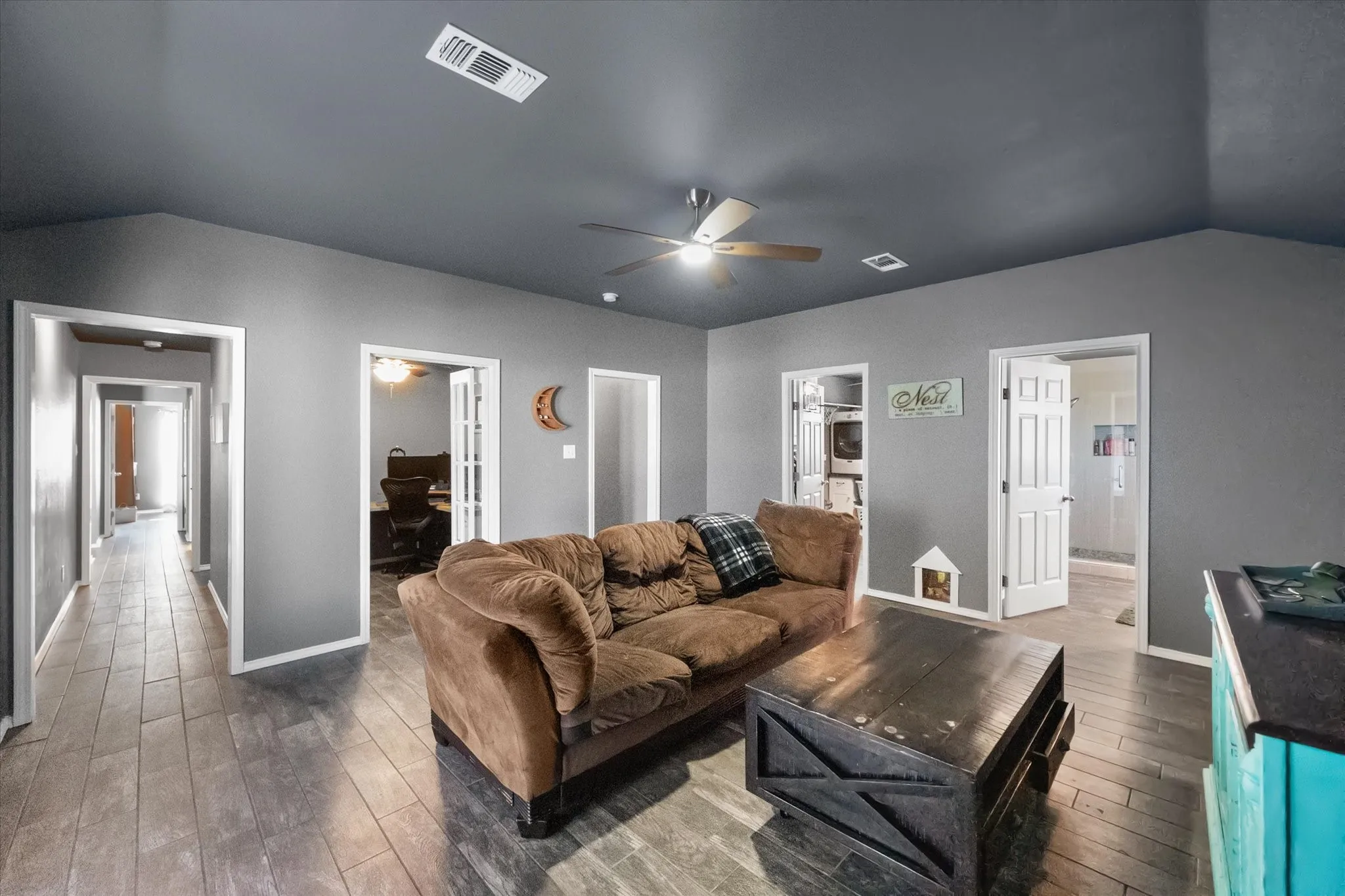 Located at back of the home, this room is a great place for family GAME NIGHTS   Vfaulted ceiling with a ceiling fan, wood-finish flooring, and multiple doorways leading to additional rooms