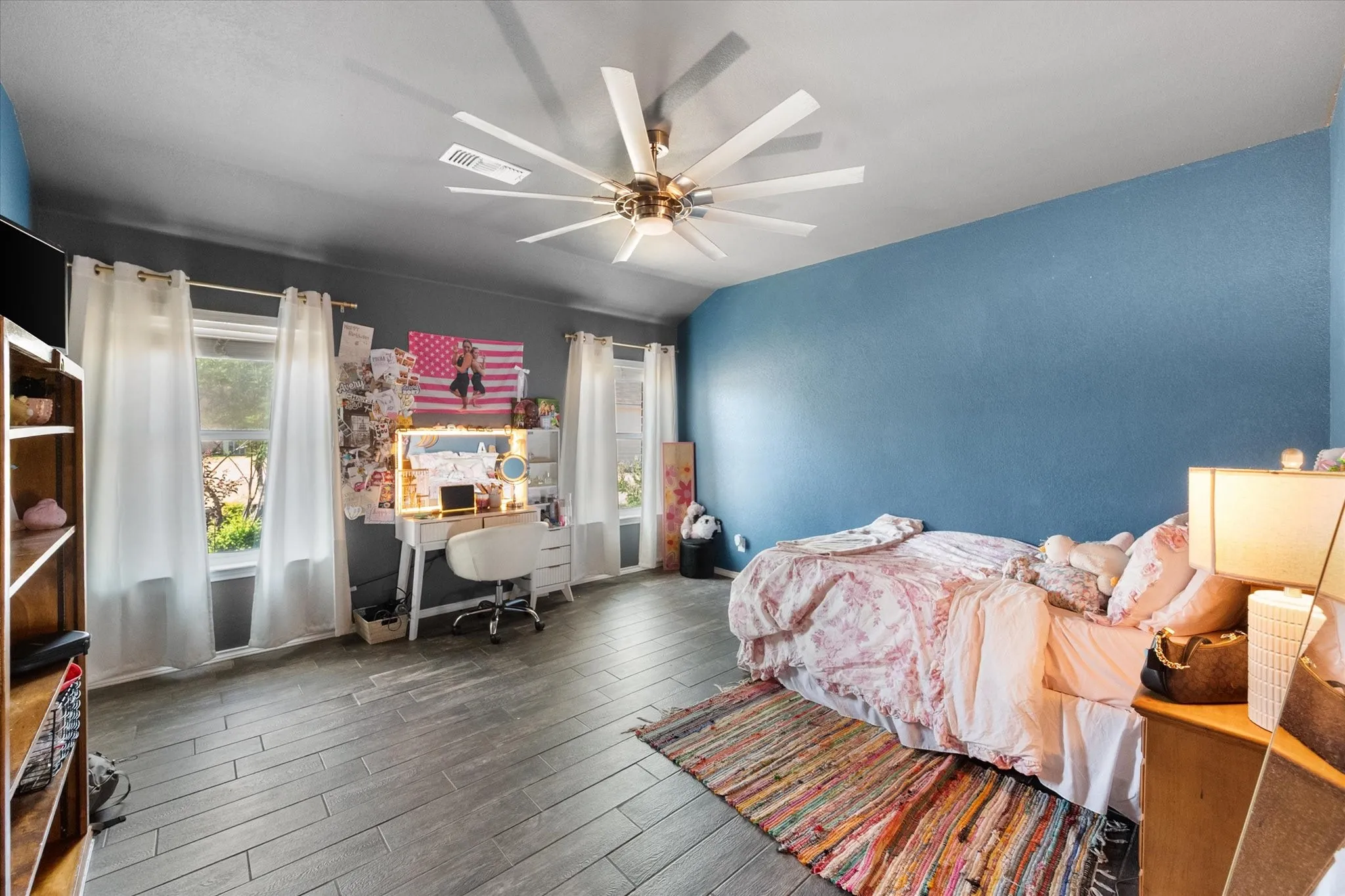 Wood-finish flooring, multiple windows, a ceiling fan, and painted accent walls