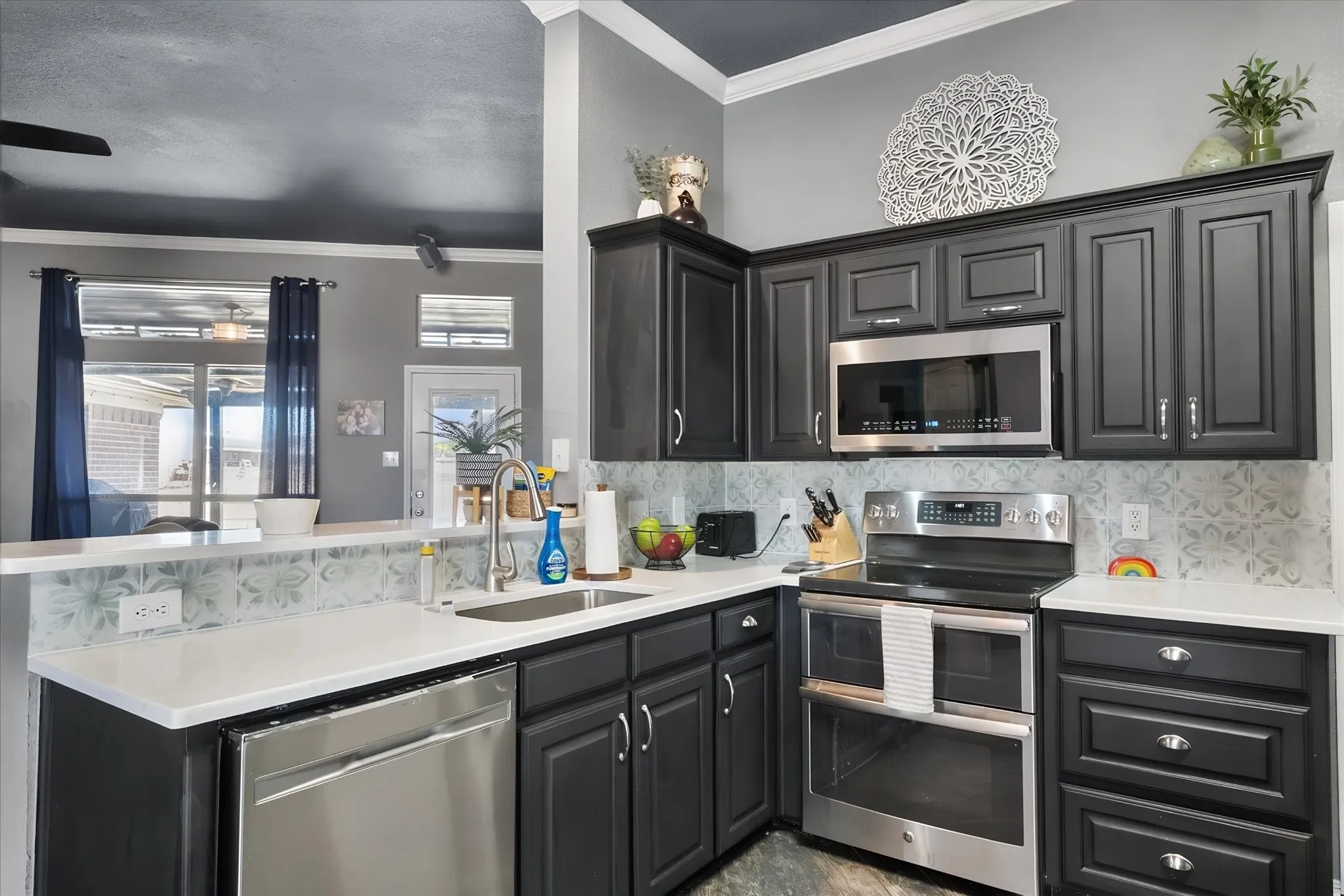 Kitchen featuring dark wood cabinetry, white countertops, stainless steel appliances, and a patterned backsplash