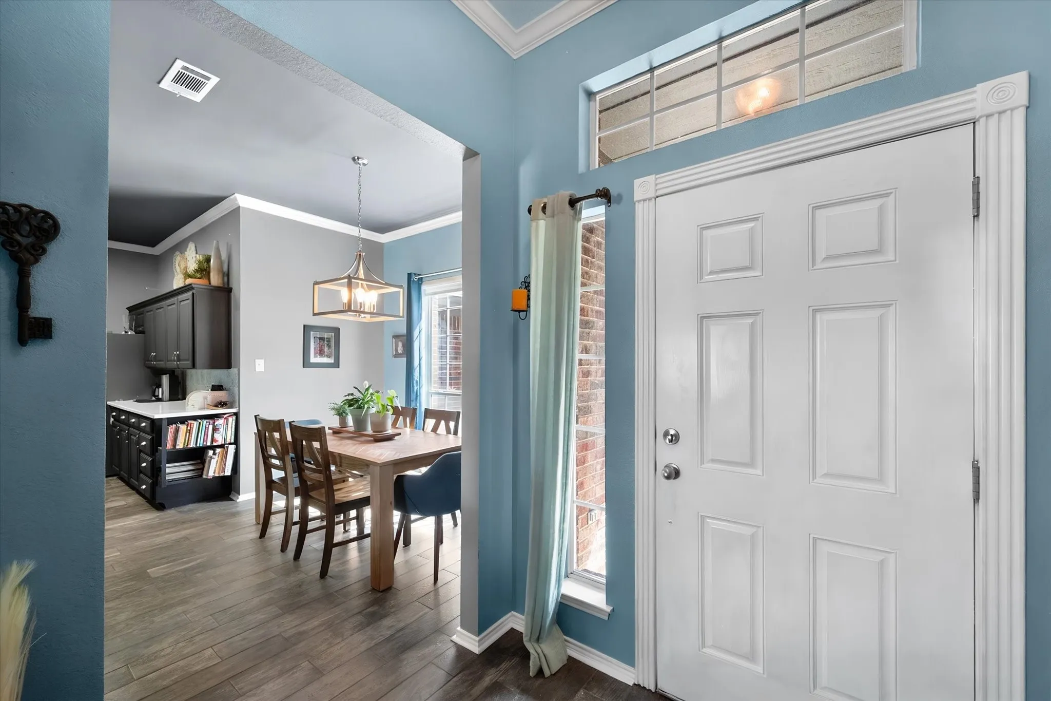 Recessed lighting, wood-finish flooring, crown molding, a built-in pantry cabinet, and a transom window above the entry door