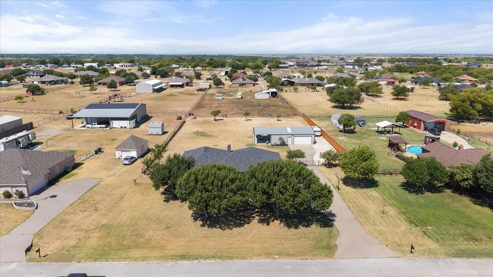 Expansive property featuring multiple outbuildings, mature trees, and a concrete driveway