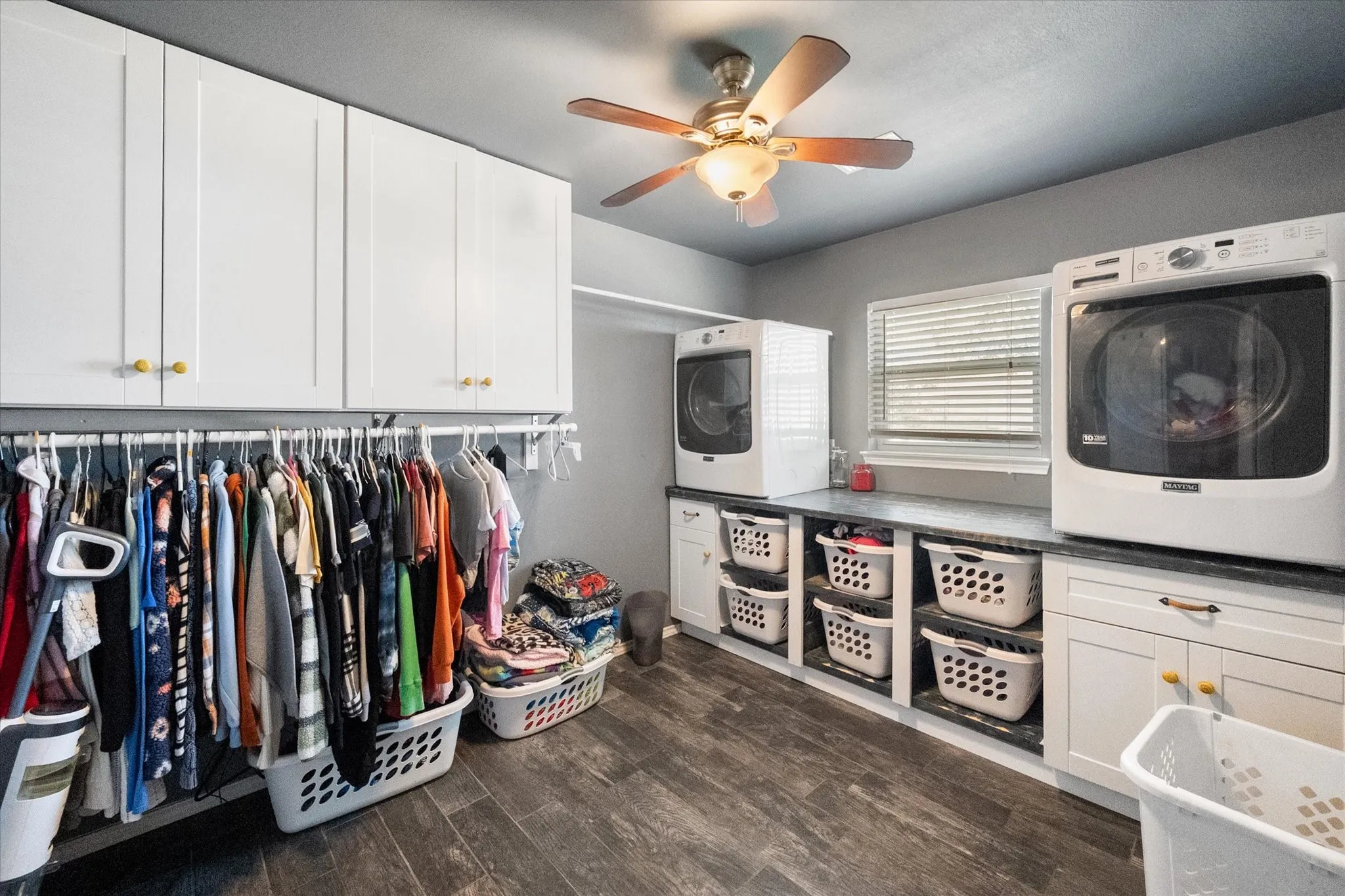 Wood-finish flooring with white cabinetry and dark countertops