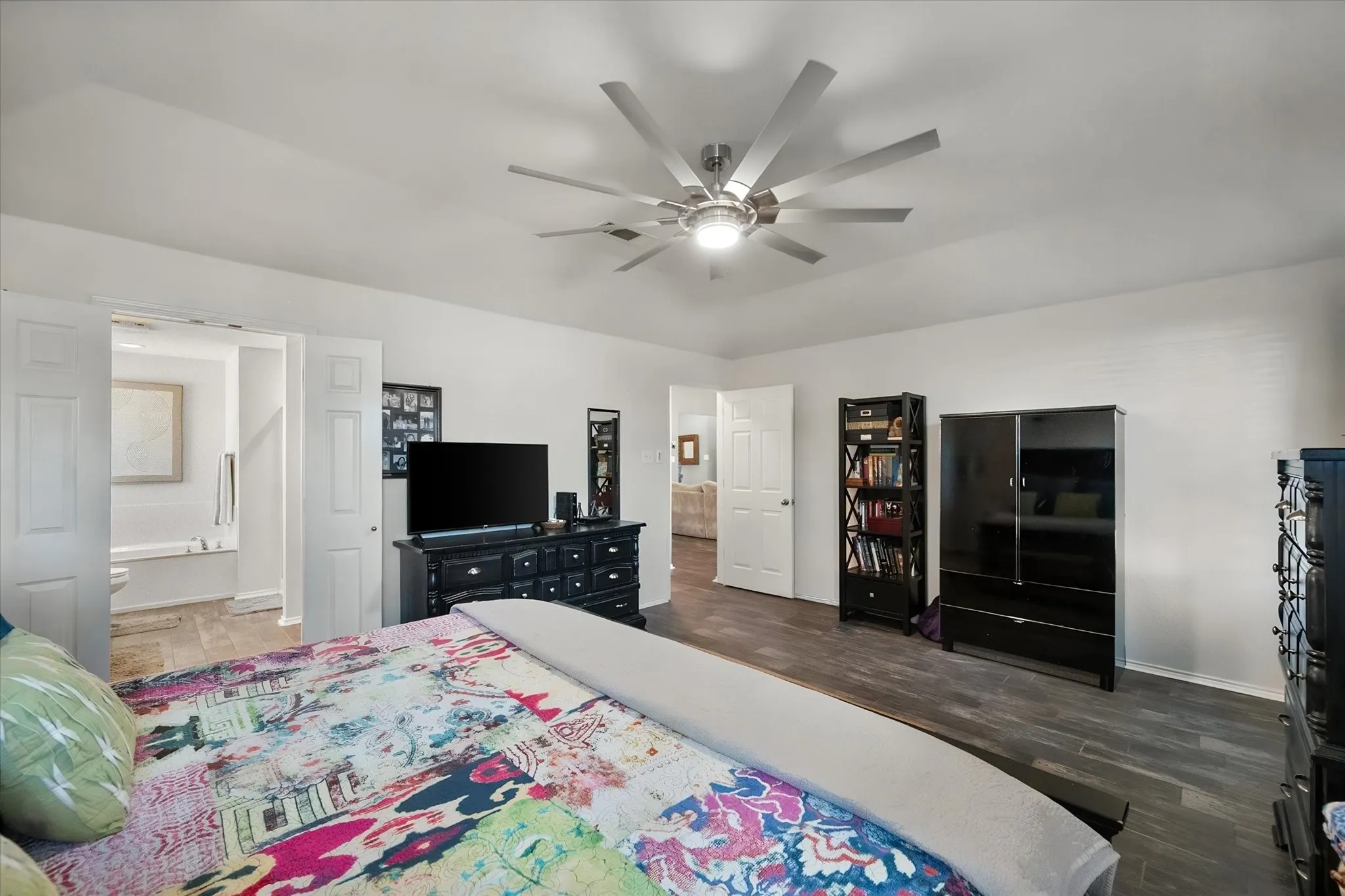 Vaulted ceiling with a contemporary ceiling fan, wood-finish flooring, and white interior doors