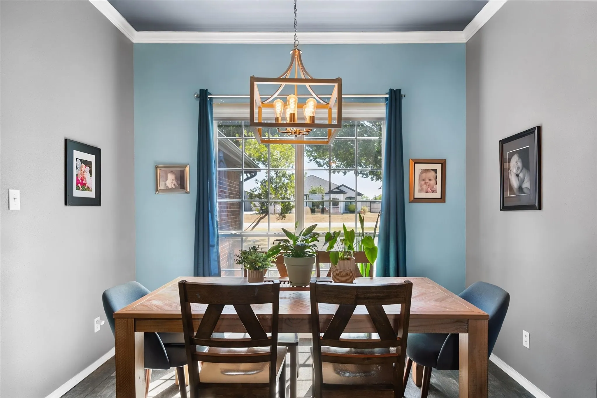 Hardwood-finish flooring, accent wall with window, crown molding, and a decorative ceiling light fixture