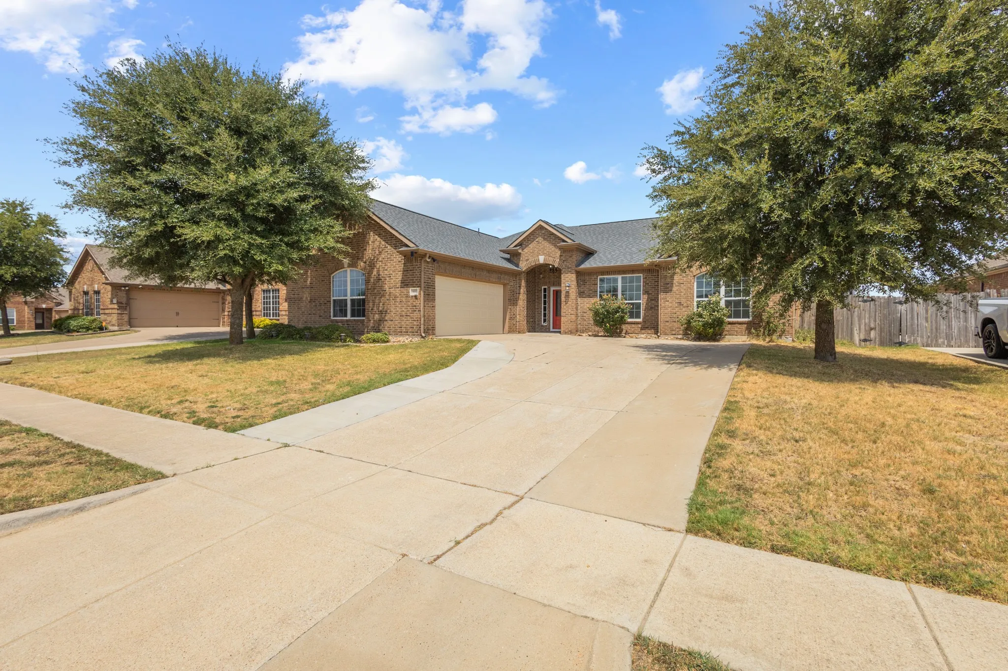 Brick exterior home with an attached garage, arched entry, and a concrete driveway