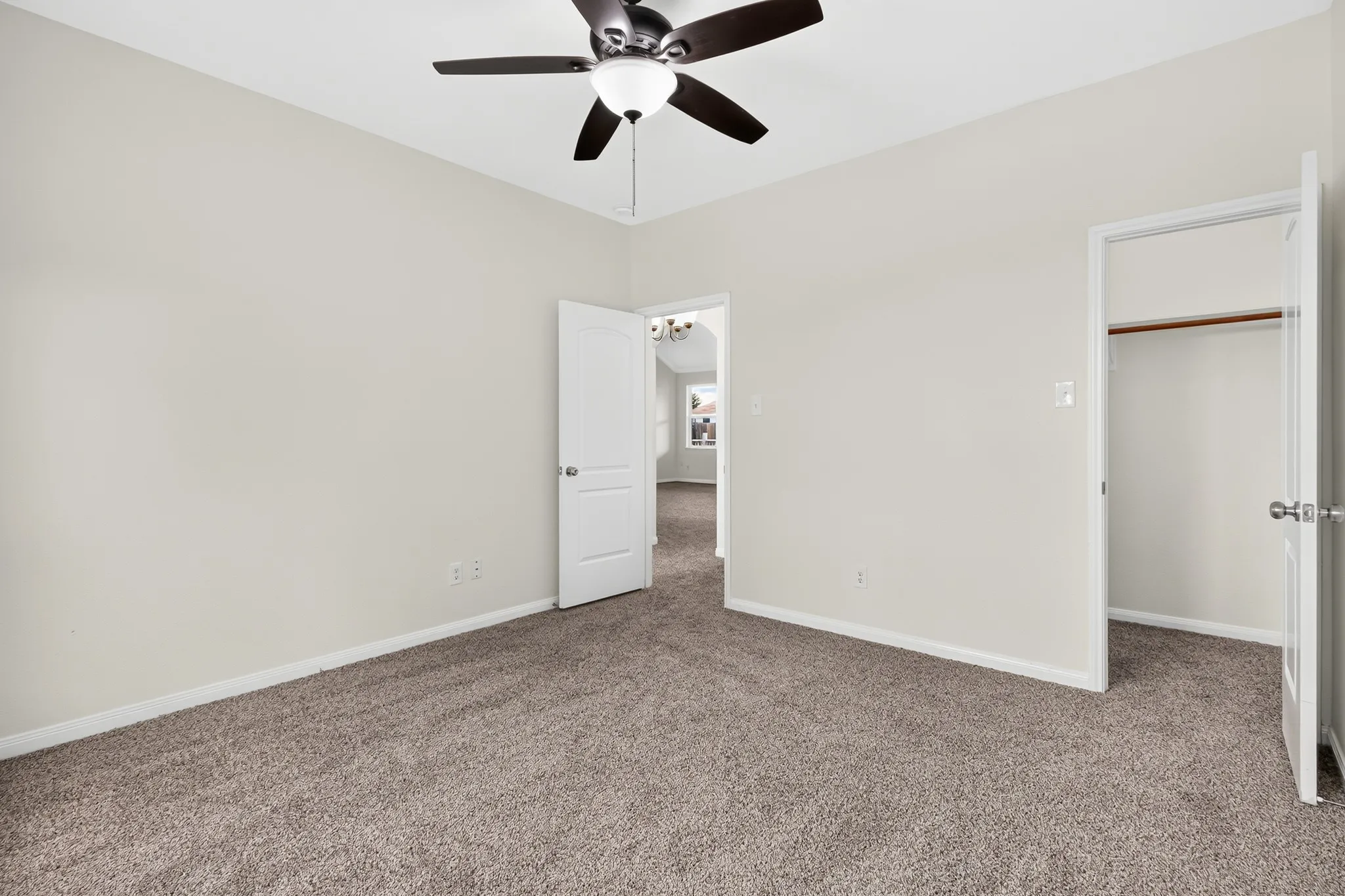 Plush carpeting, neutral wall tones, and a ceiling fan with integrated lighting