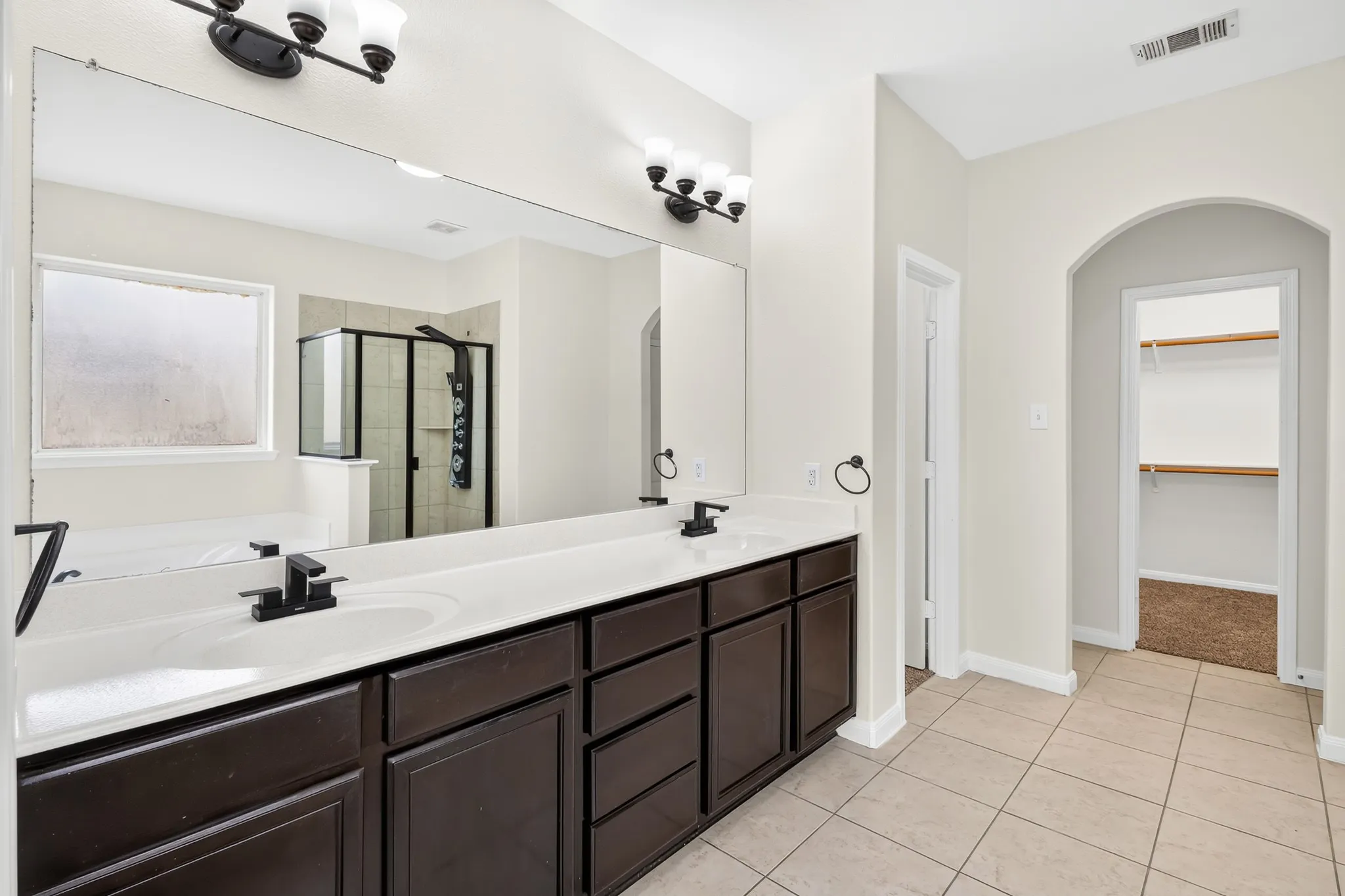 Dual vanity with dark wood-finish cabinetry, white countertop, and matte black fixtures