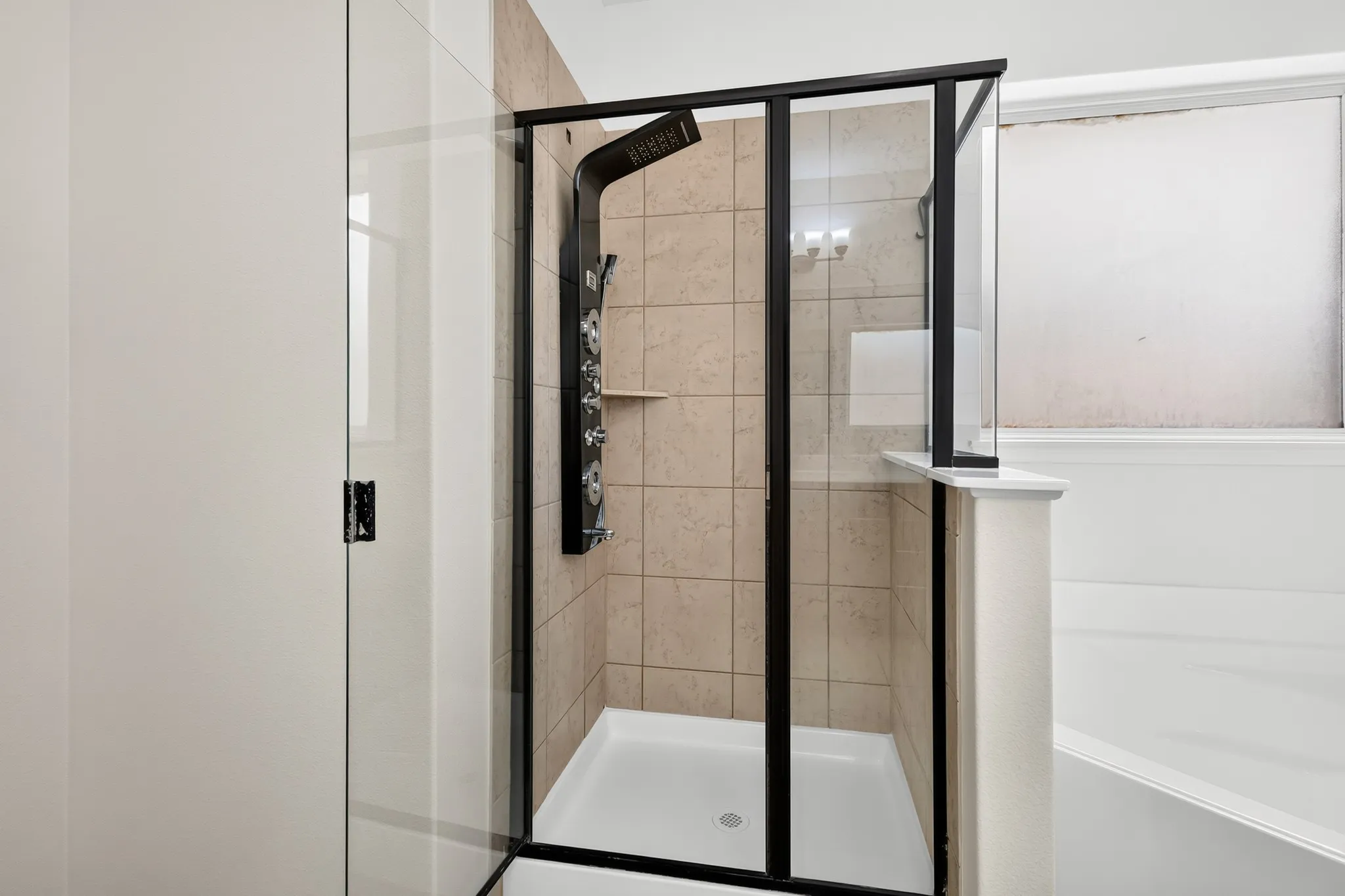 Glass-enclosed shower with a black-framed door and a tiled interior