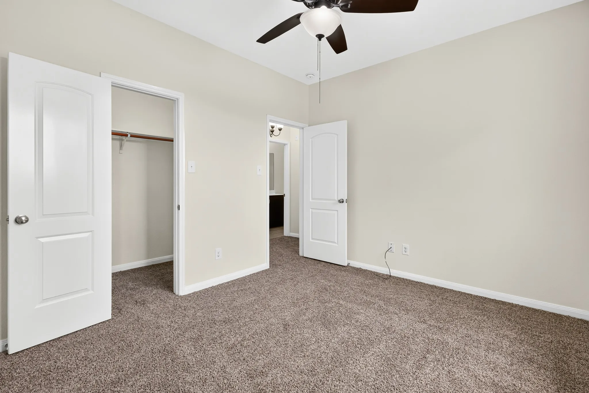 Carpeted flooring, ceiling fan with integrated lighting, white interior doors, and a closet with a hanging rod
