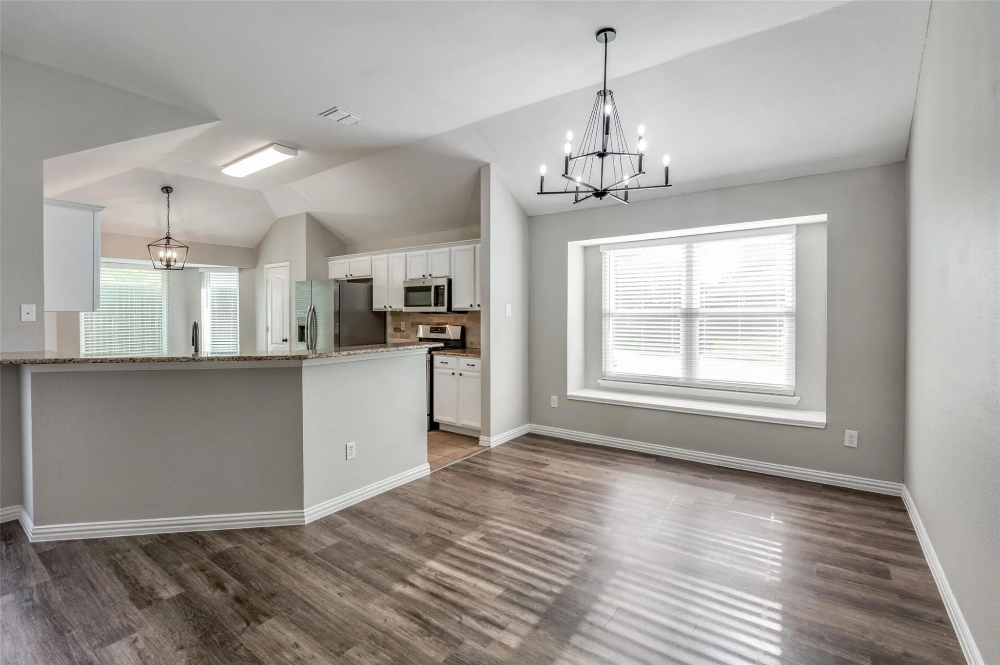 Varnished wood-finish flooring, a contemporary chandelier, and an expansive window with a deep sill