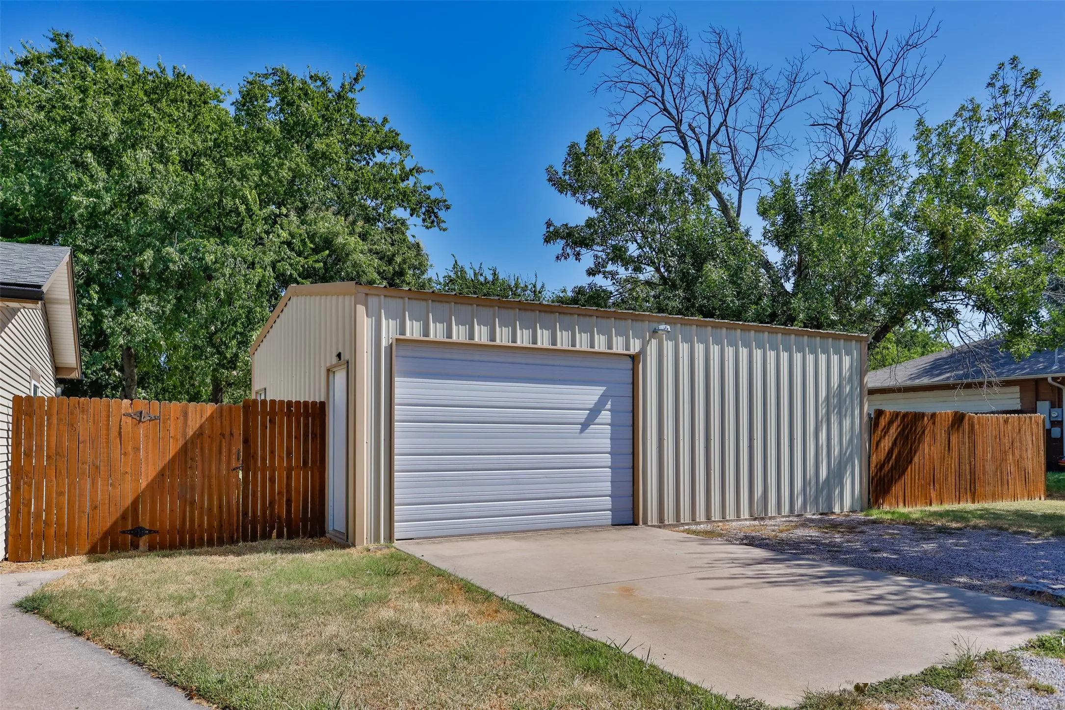 Metal outbuilding with a roll-up garage door, pedestrian entry, and concrete driveway