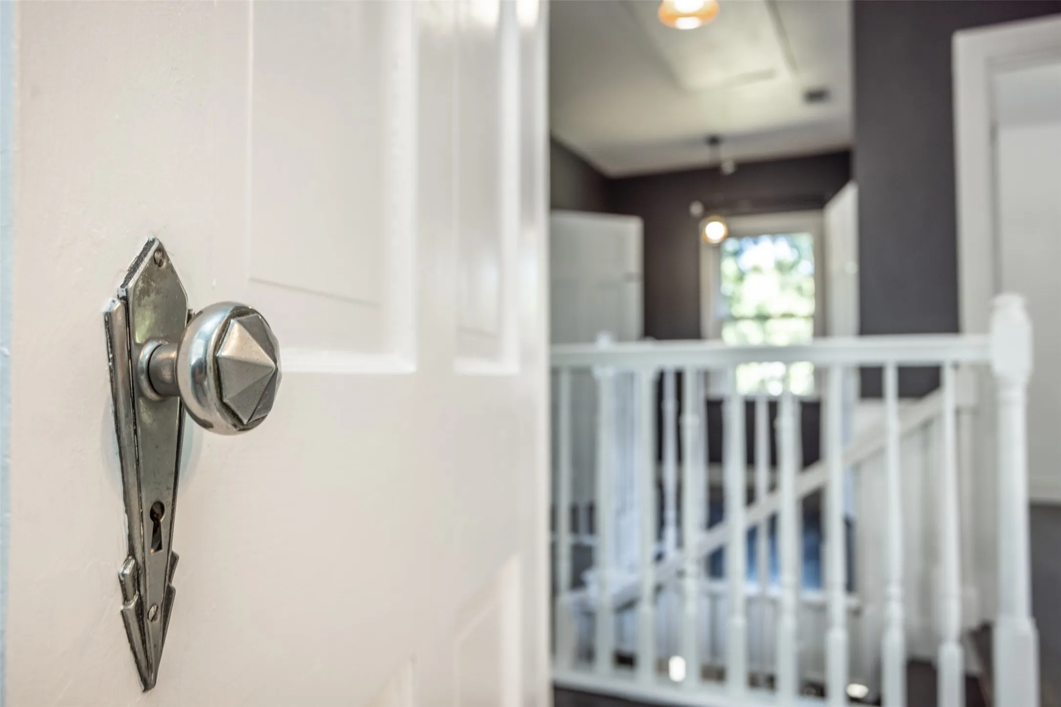 White paneled door with faceted knob, dark wall accents, and white painted balusters