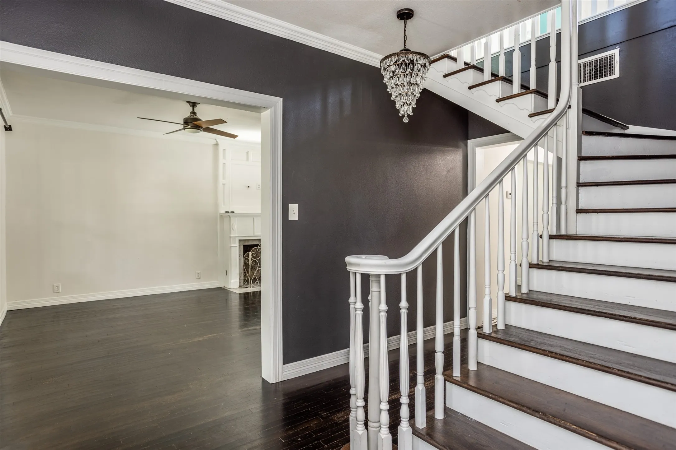 Staircase with dark wood-finish treads and white risers, featuring a white balustrade and handrail