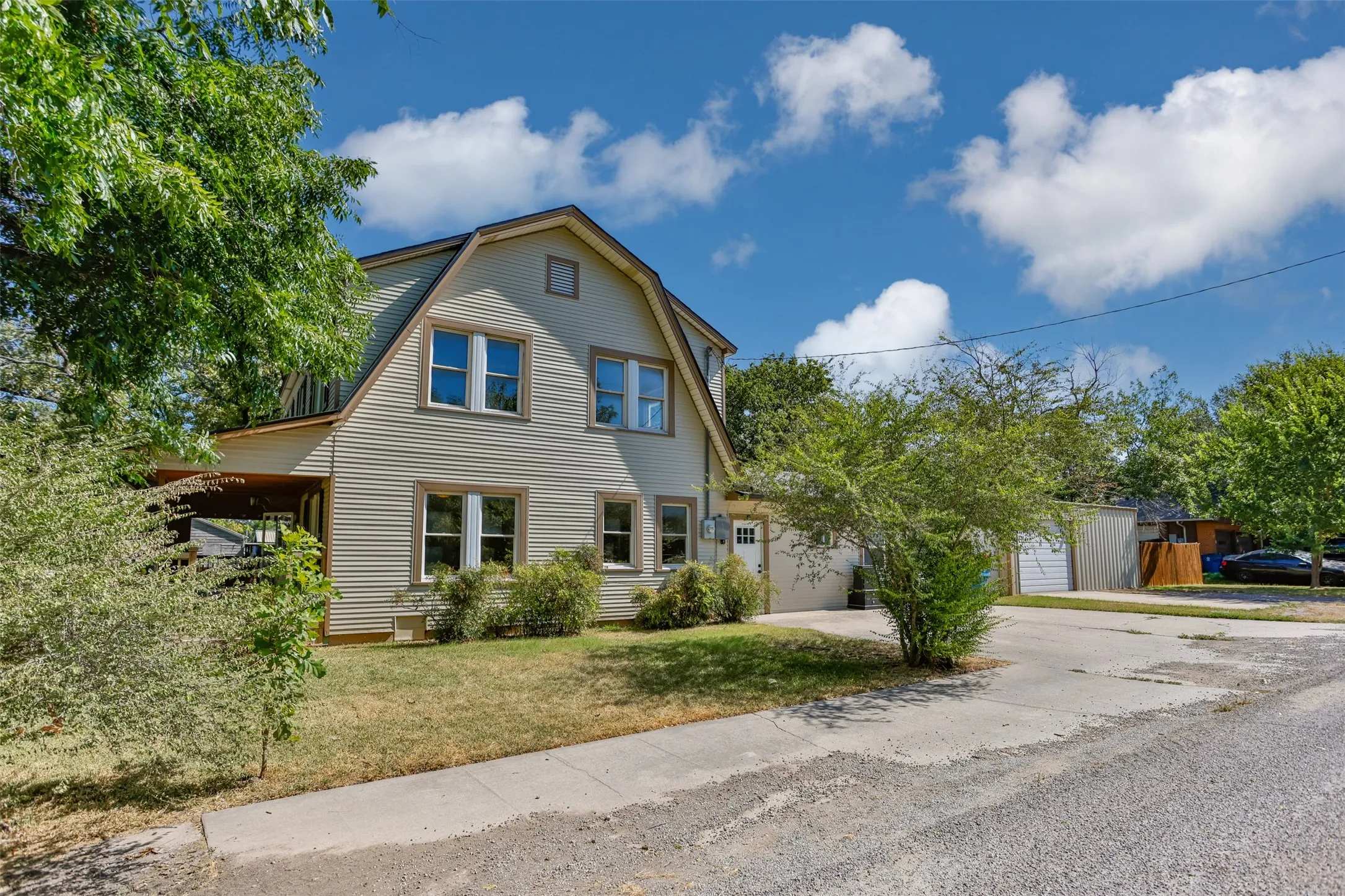 Gambrel roofline, horizontal siding, multiple windows, attached garage, paved driveway