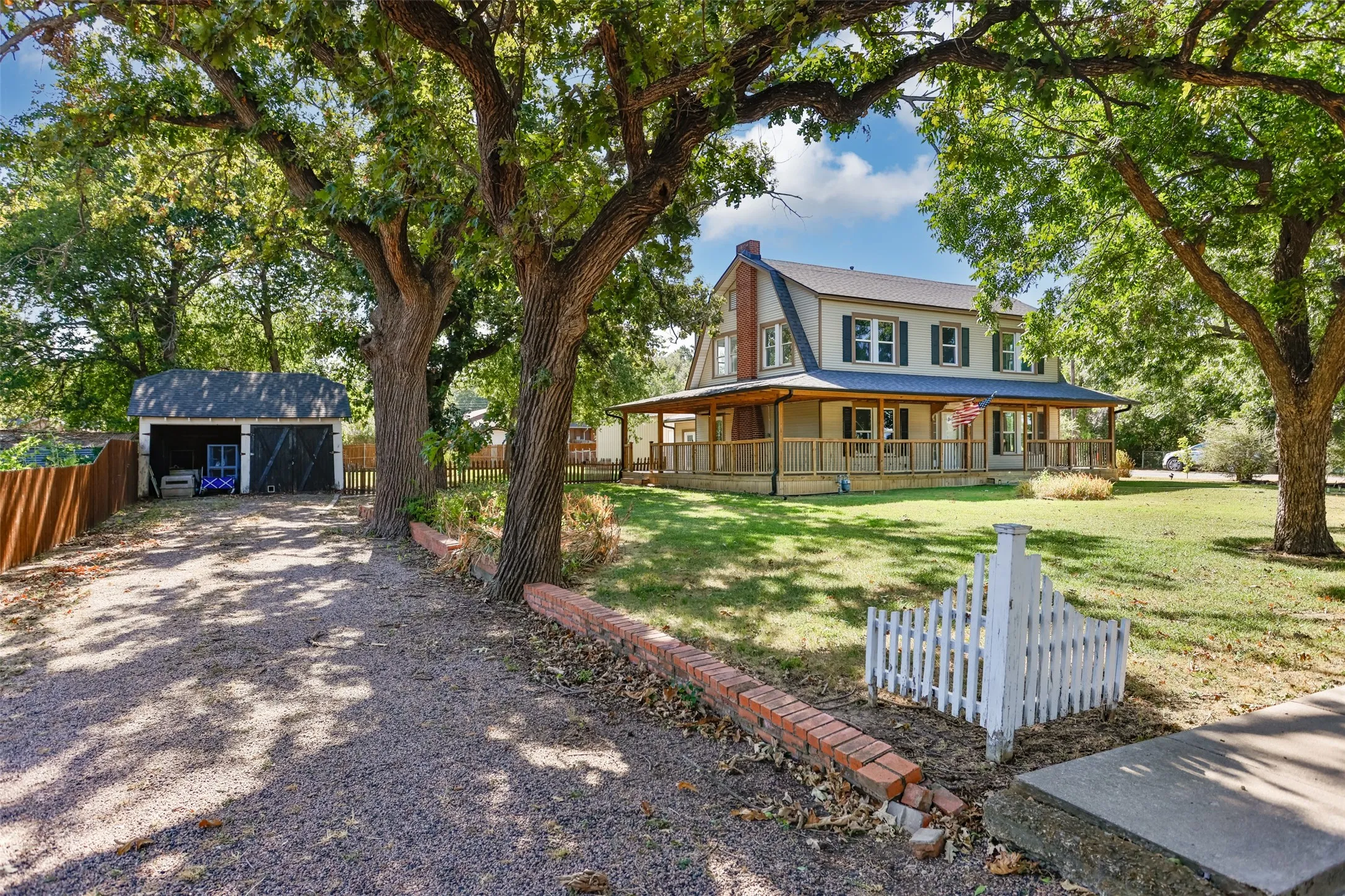 Two-story residence featuring a covered wrap-around porch and a detached two-car garage with double barn doors