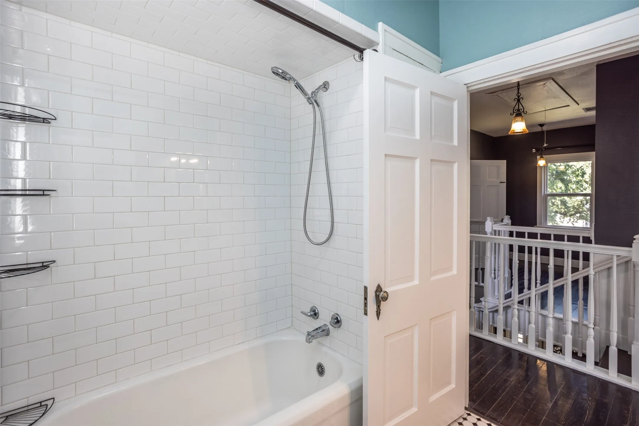 Subway tile surround, chrome fixtures, built-in shelving, white paneled door, and dark wood-finish flooring