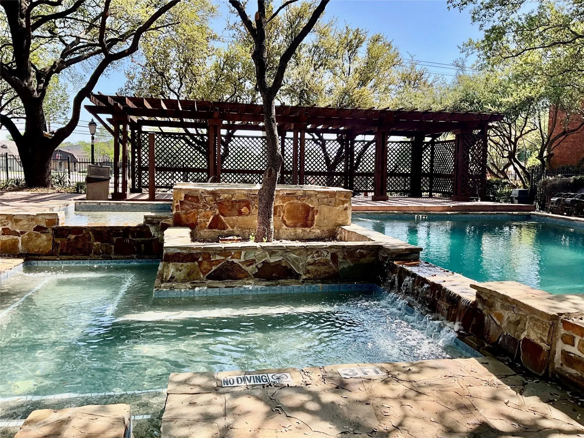 Swimming pool with stone-clad retaining walls, integrated spa, and an expansive wooden pergola with lattice detailing