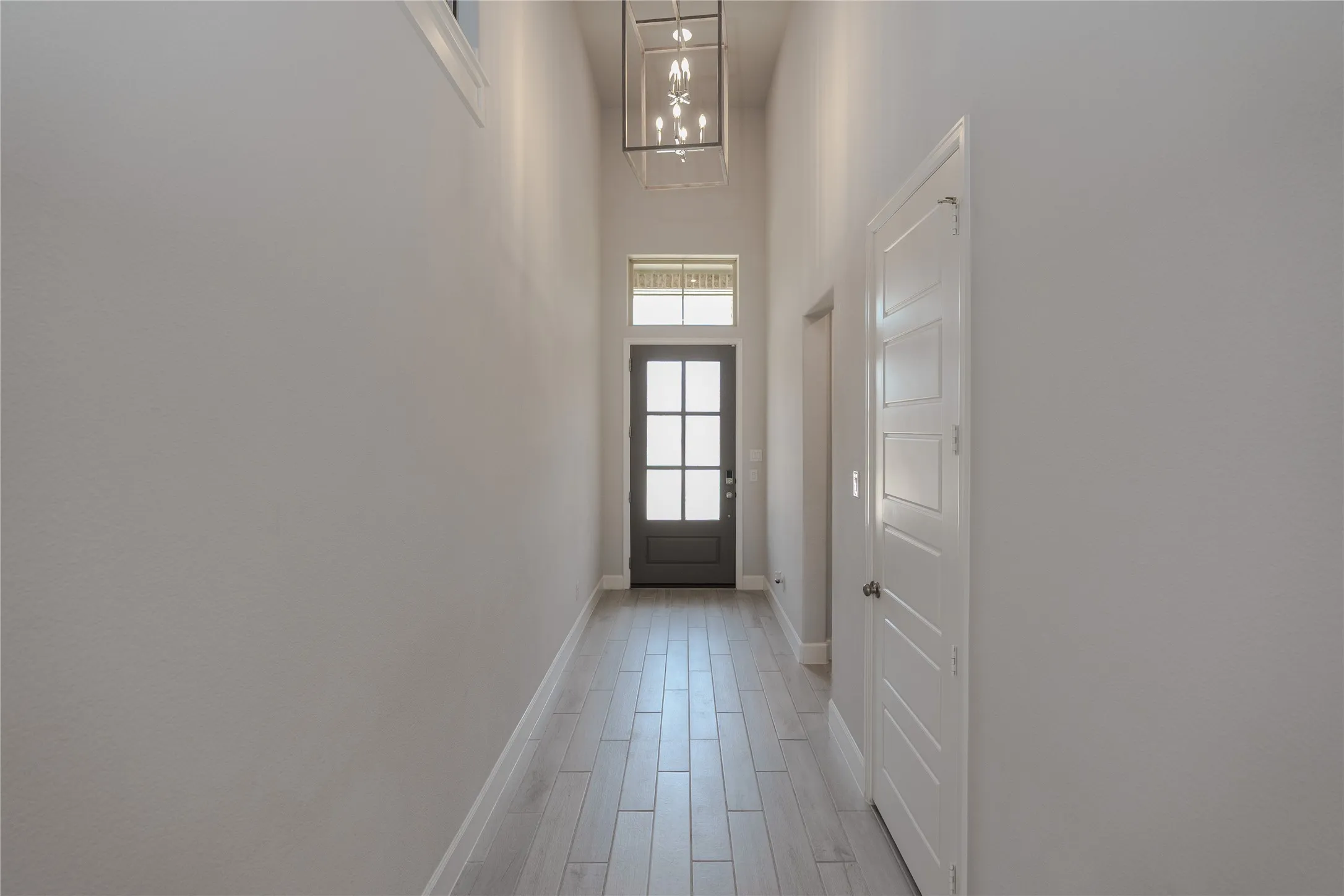 Foyer featuring wood-finish flooring, a dark-paneled door with glass inserts, and a transom window
