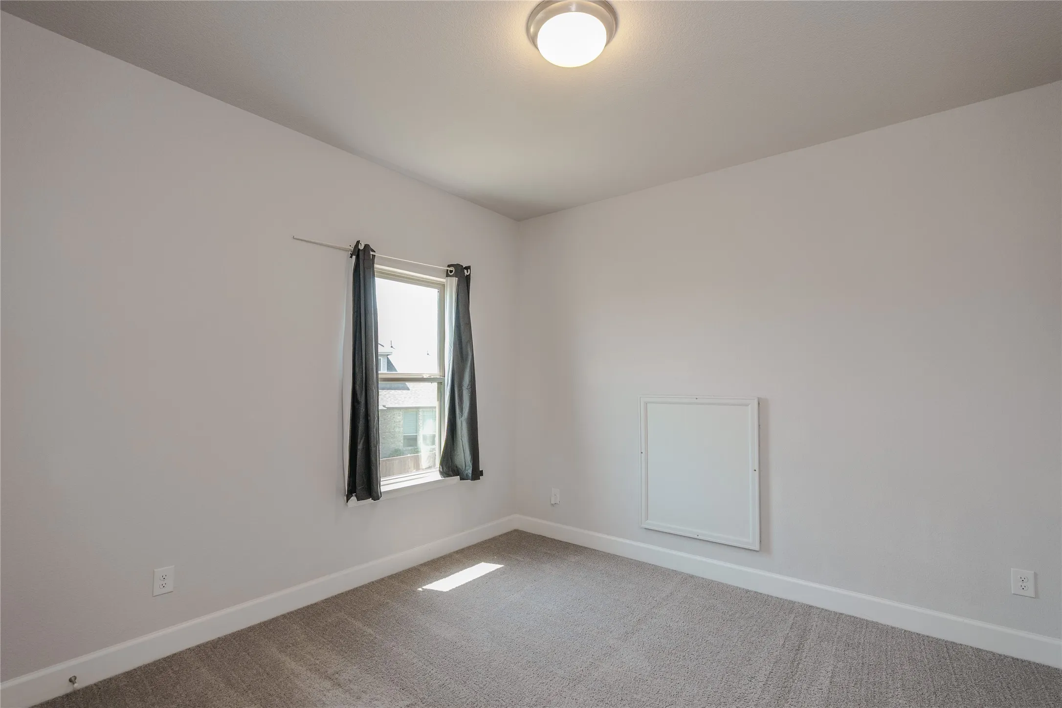 Recessed window with natural light, light gray walls, gray carpet, and a flush-mount ceiling light fixture
