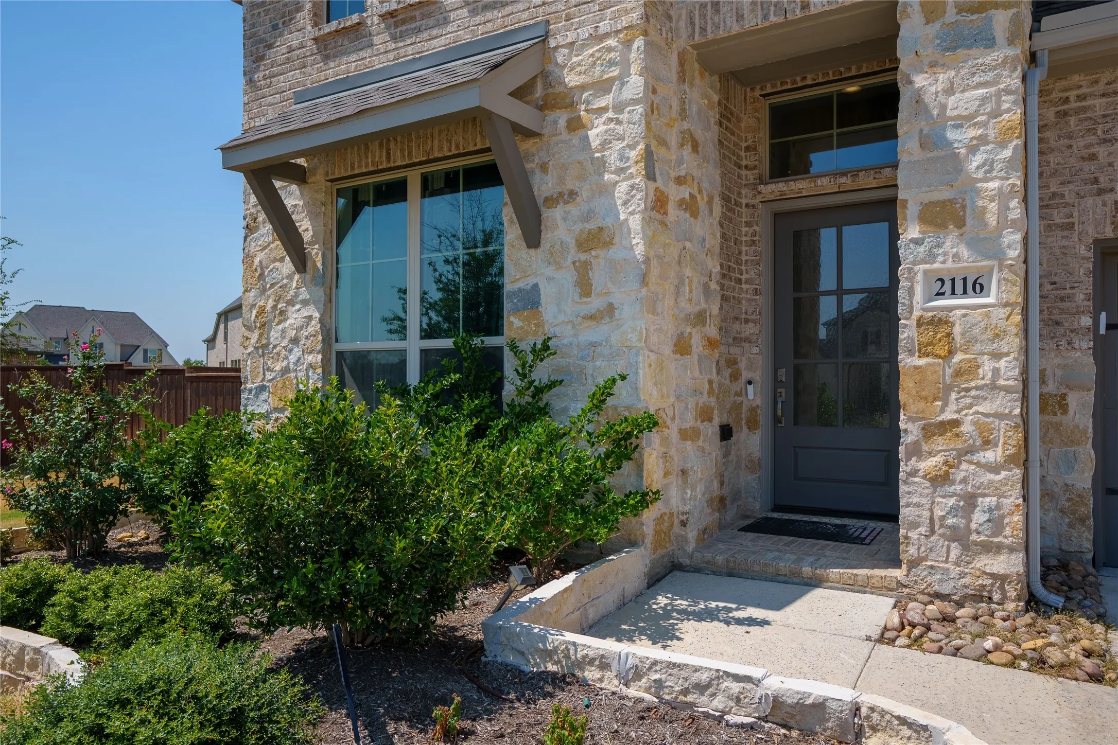 Stone and brick facade with a prominent entry door, transom window, and decorative awning