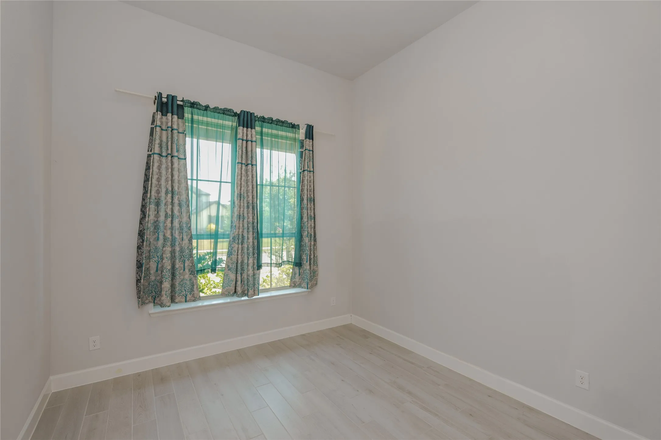 Light-toned wood-finish flooring, white wall paint, and a window with white trim