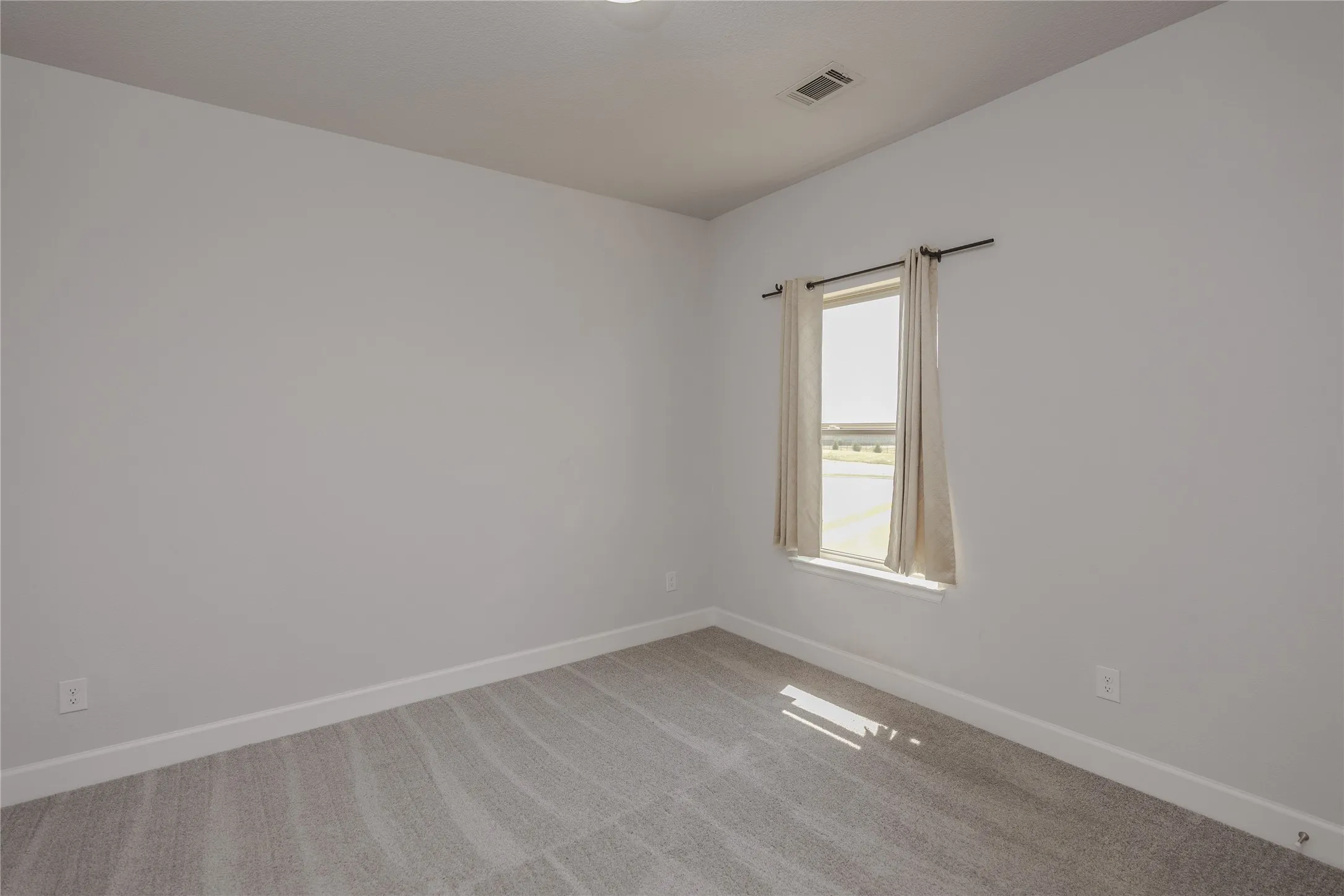 Carpeted flooring, white baseboards, window with white trim, and light gray walls