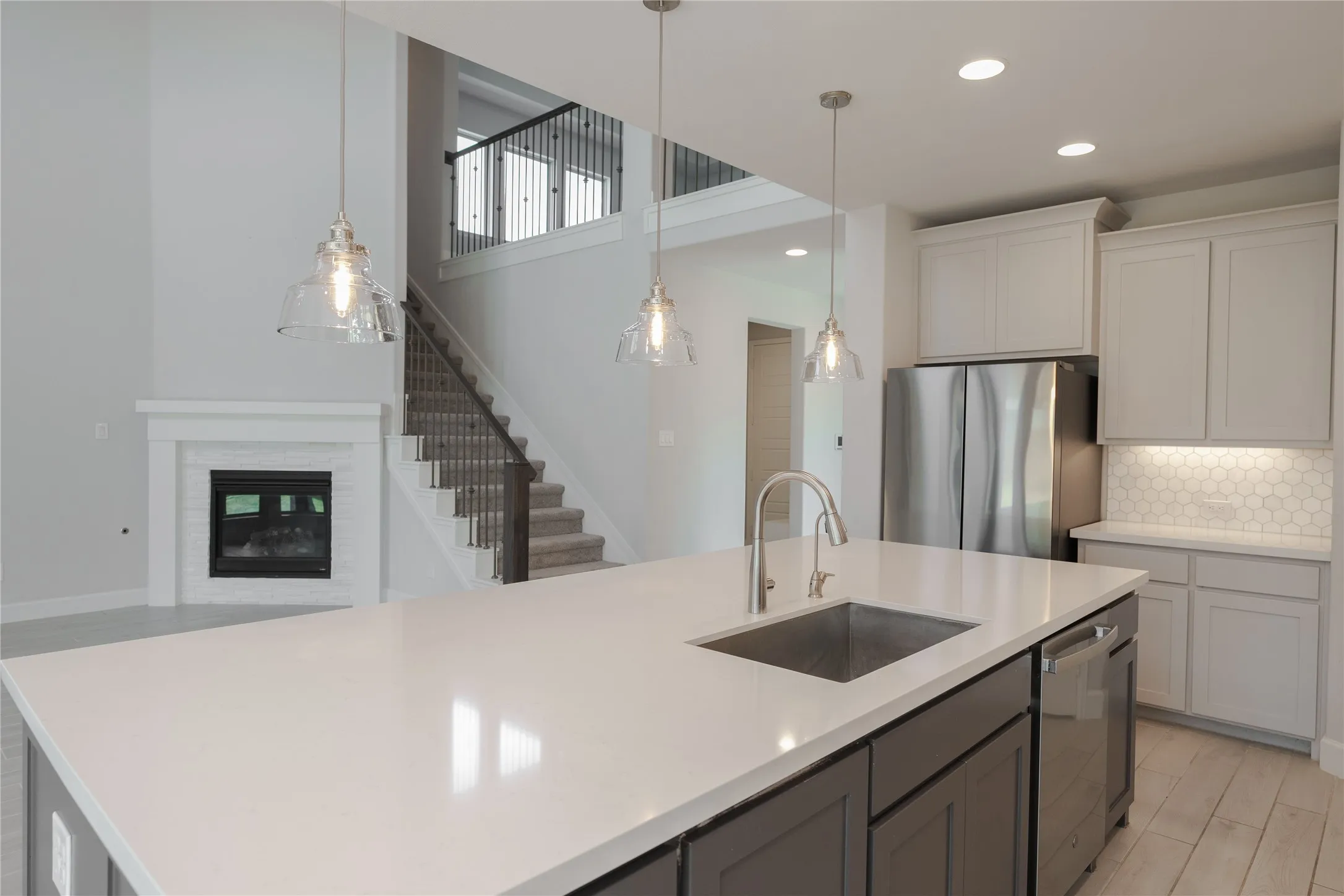 Kitchen island with an undermount sink, pendant lighting, and stainless steel appliances