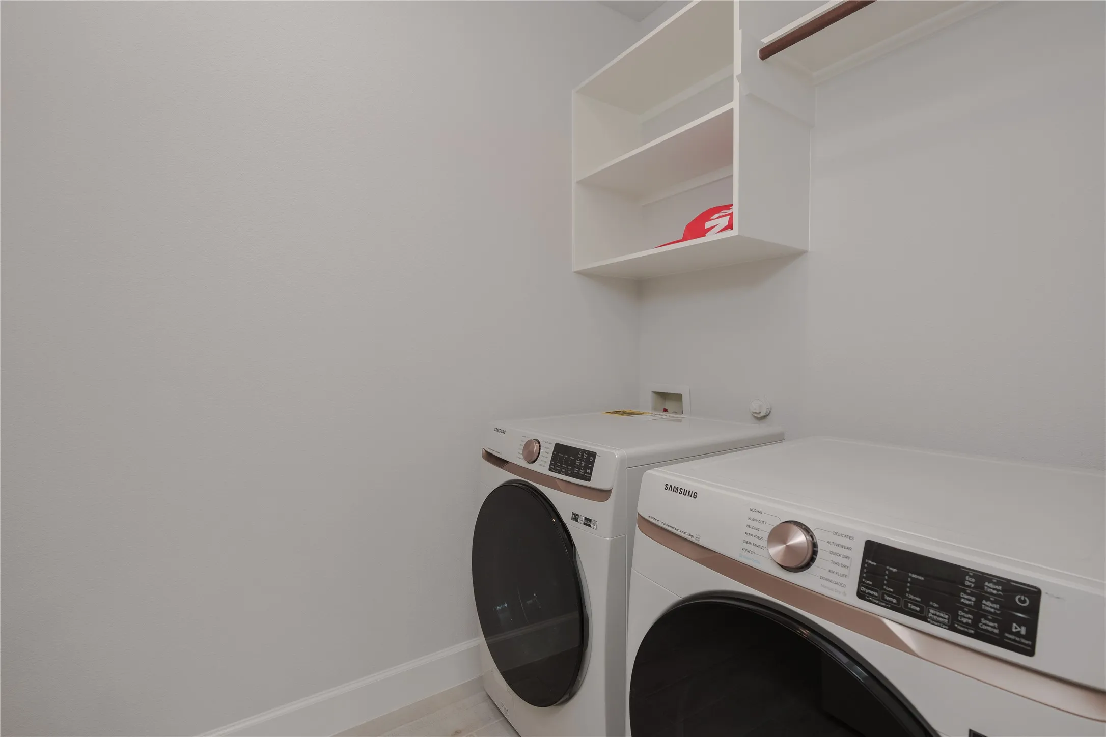 Built-in upper shelving, laundry appliance hookups, and a mounted hanging rod