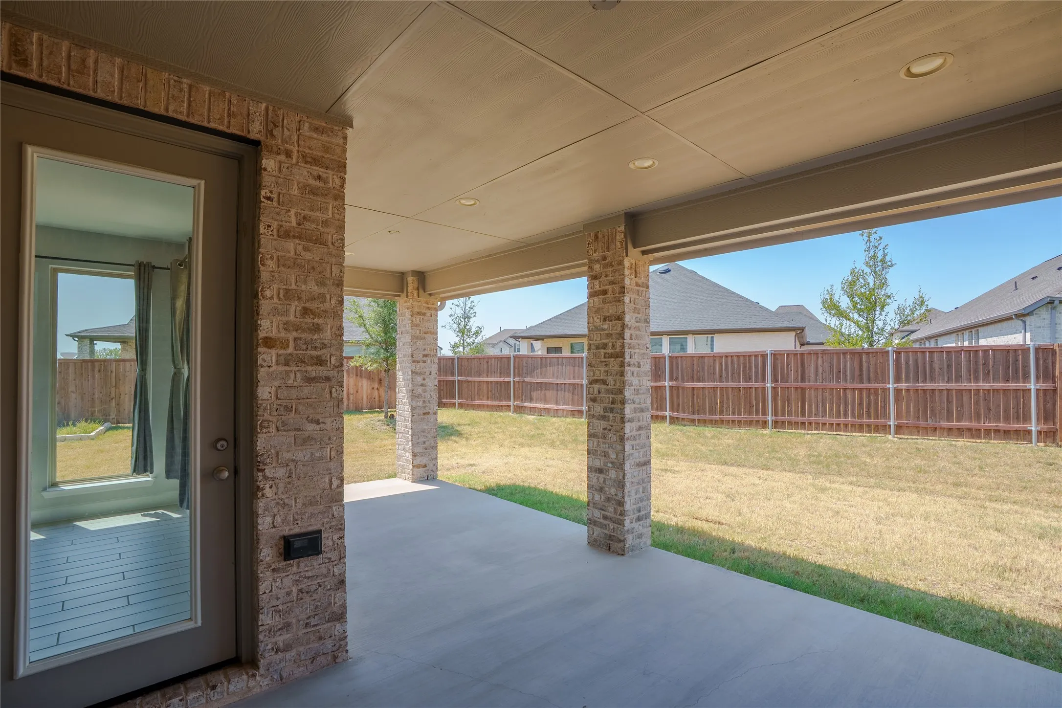 Covered patio with brick columns, recessed lighting, and a solid privacy fence