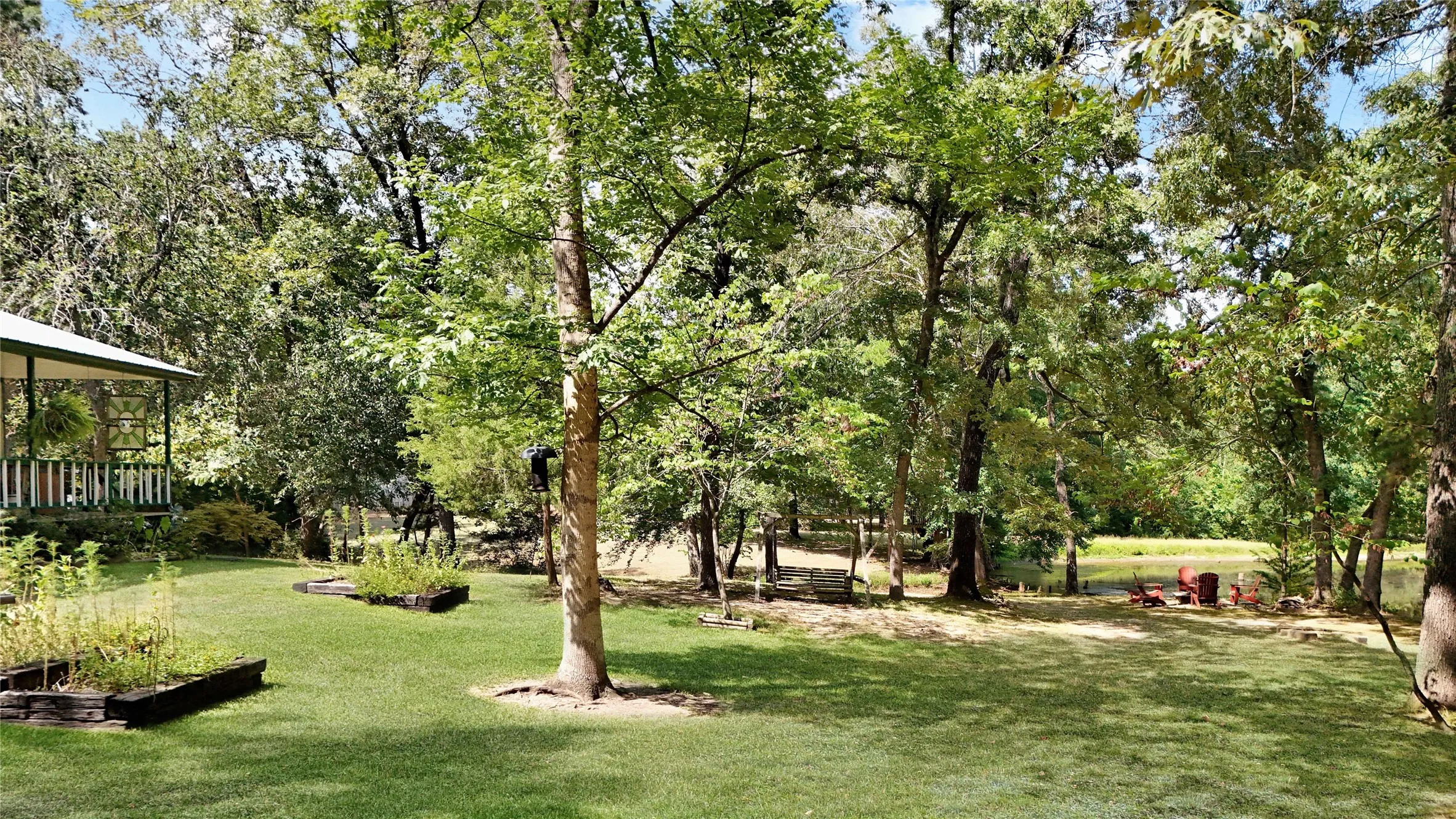 Expansive yard with mature trees, manicured lawn, and raised garden beds