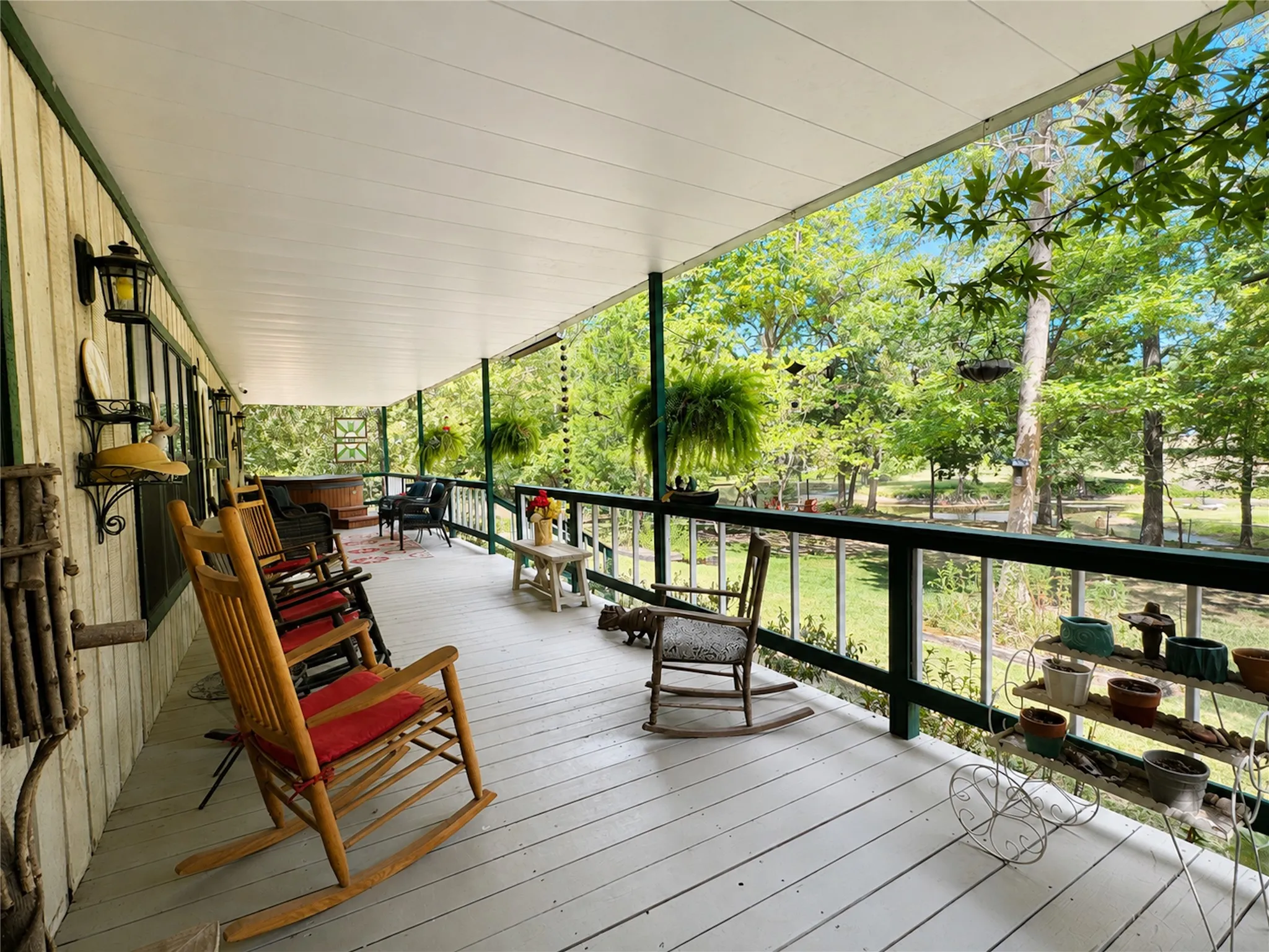 Expansive covered porch with a painted wood-finish deck and dark green railings