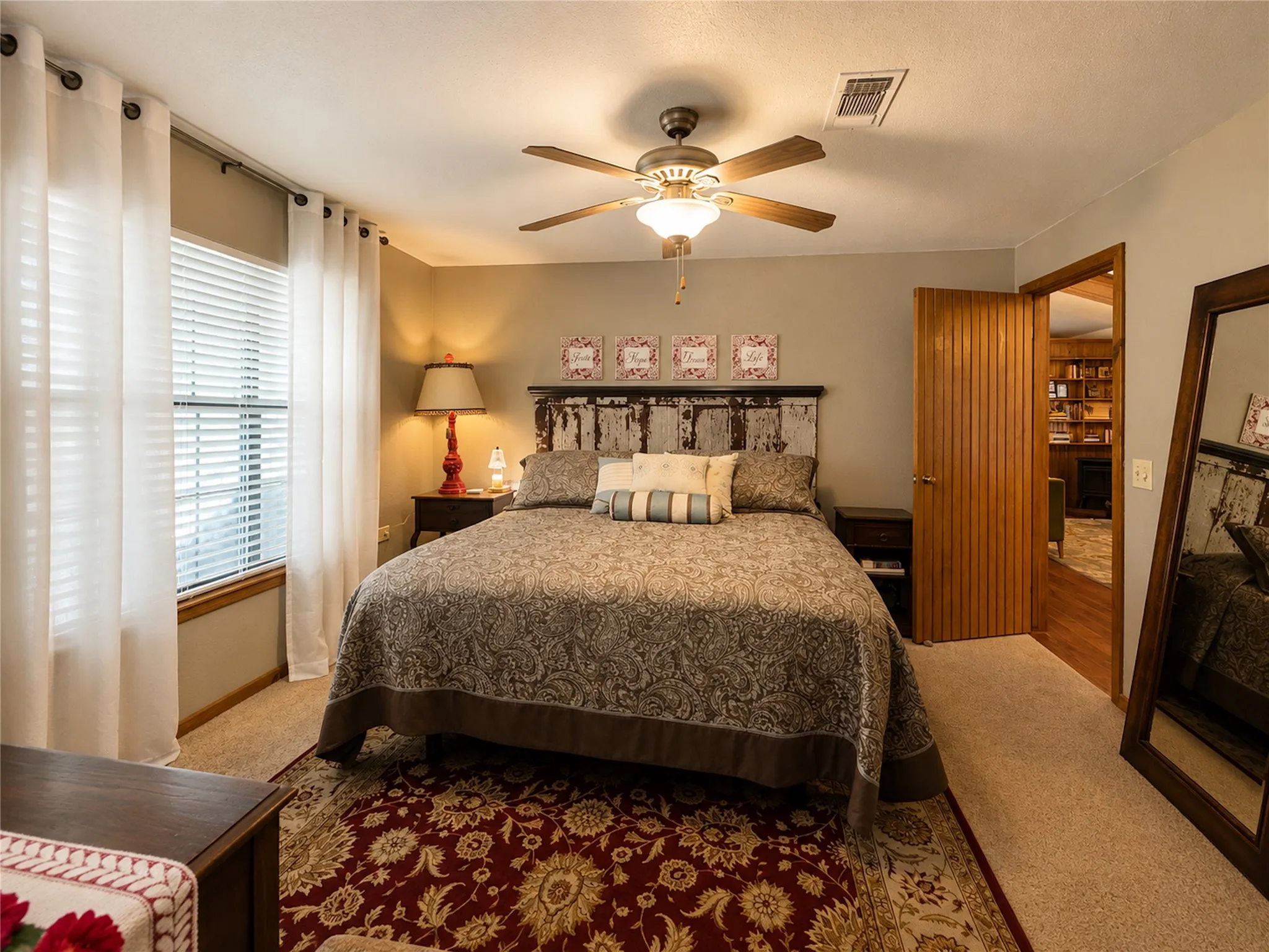Carpeted room with a ceiling fan, a window with blinds, and a wood-finish door