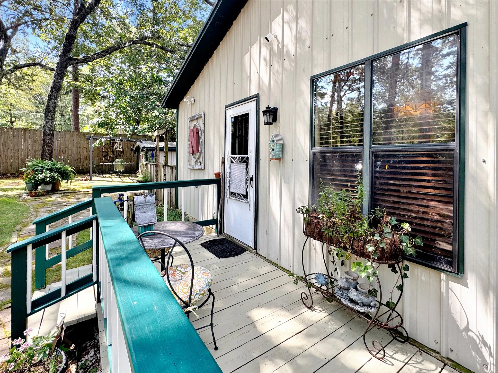 Light-colored vertical siding with a green trim window and a side entry door