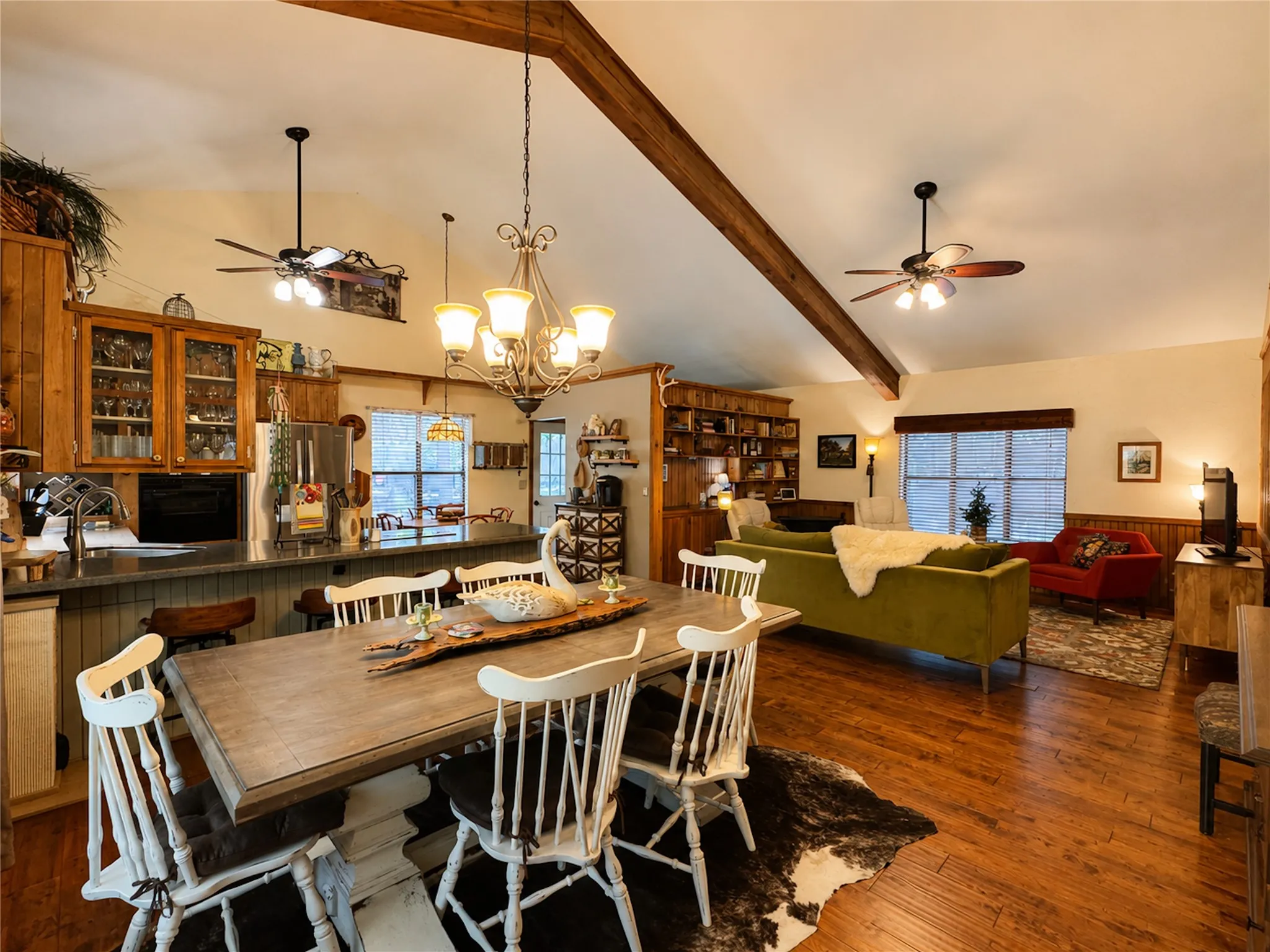 Vaulted ceilings with exposed wood beams, wood-finish flooring, recessed lighting, and a built-in bookcase