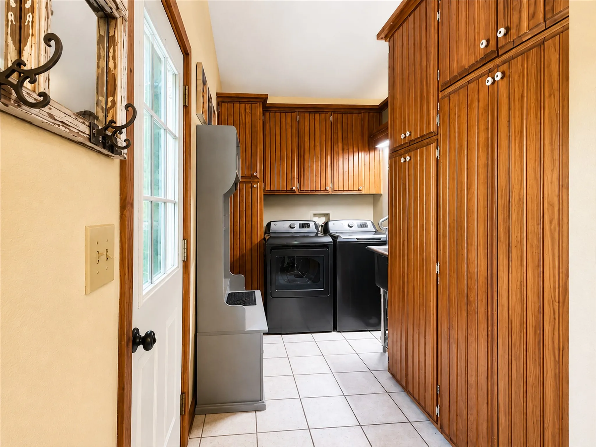 White ceramic tile flooring, wood-finish cabinetry, and built-in upper storage