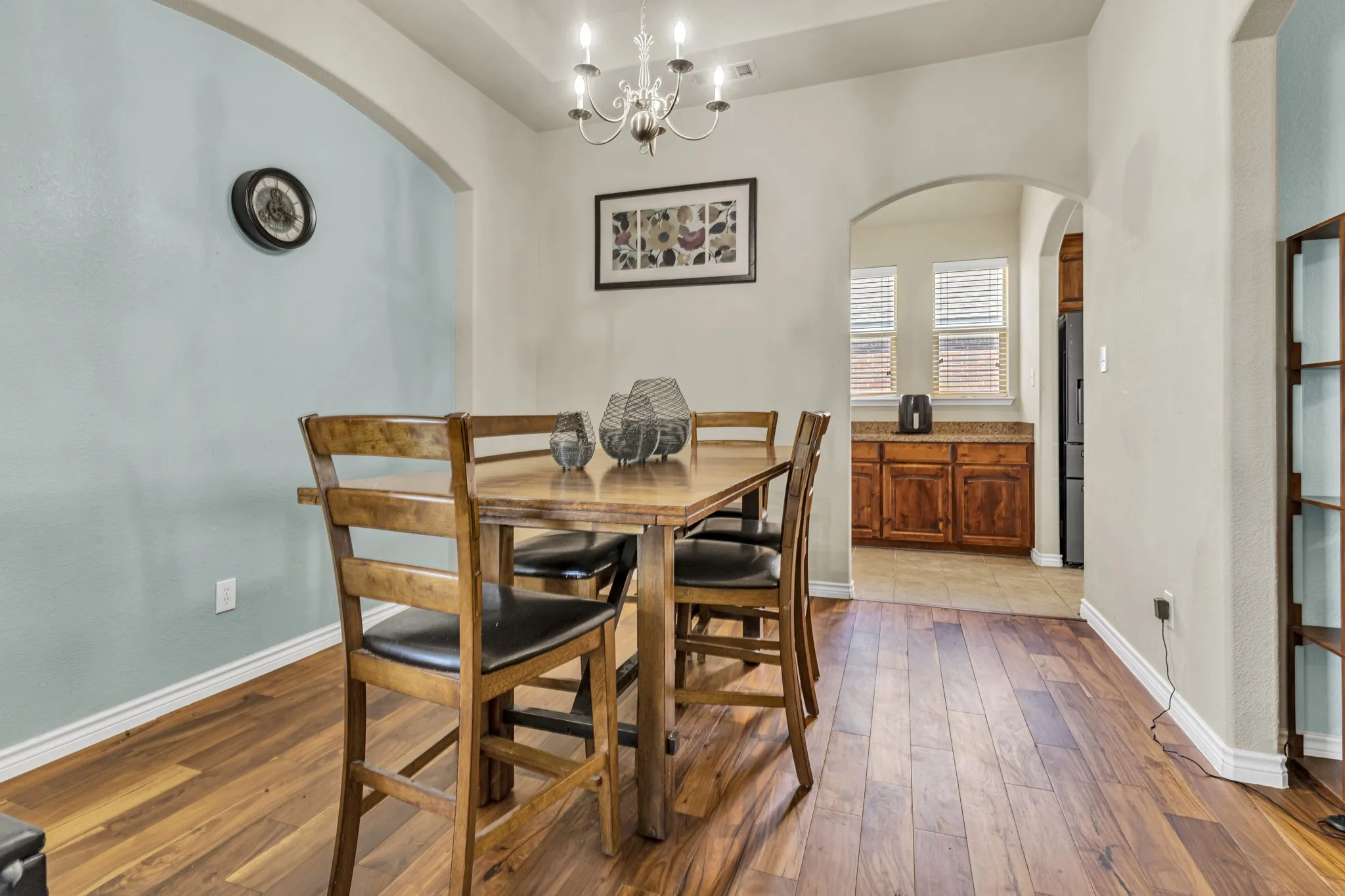 Wood-finish flooring, arched doorways, a built-in light fixture, and a light-toned accent wall
