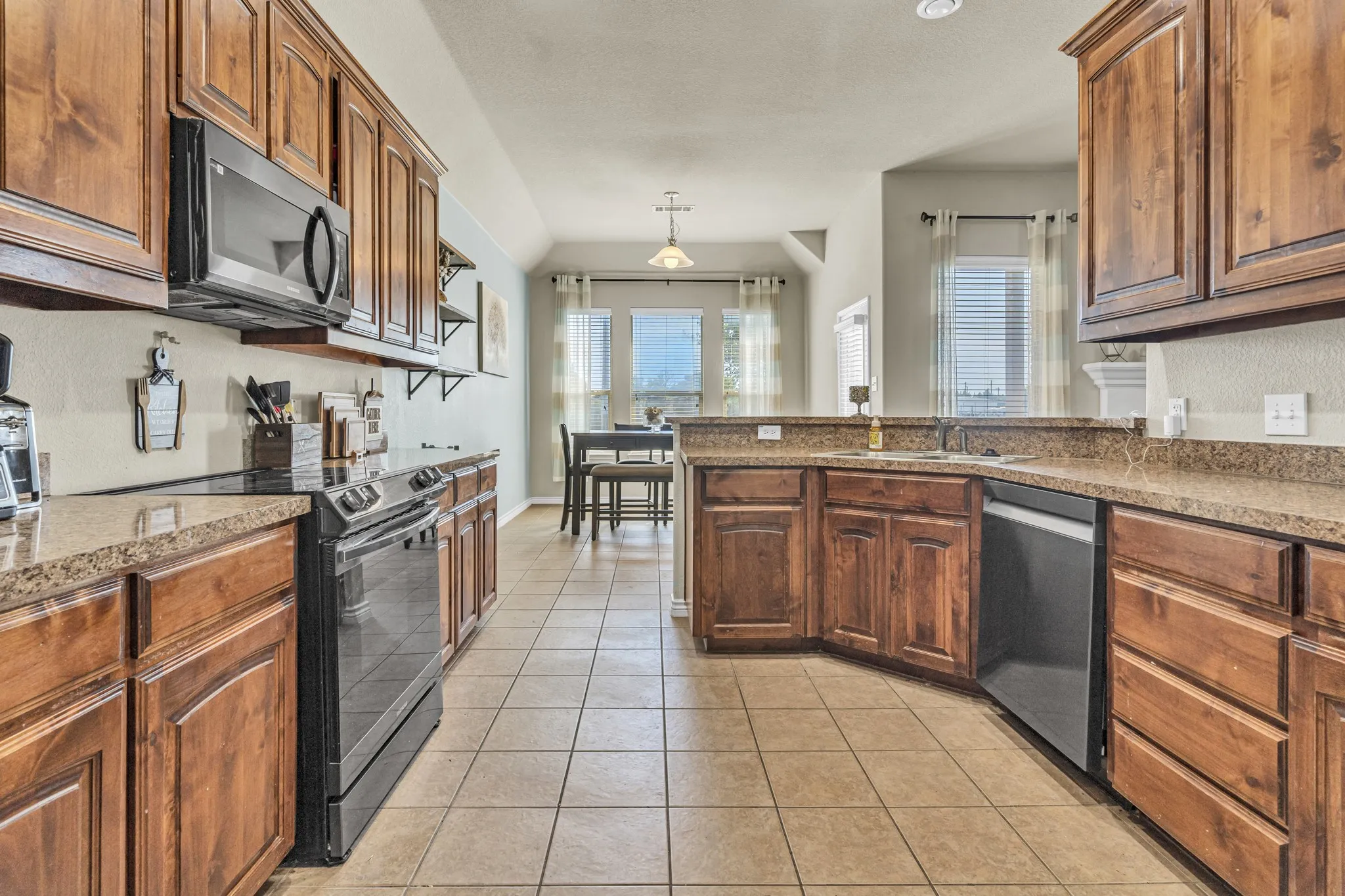 Kitchen featuring wood cabinetry, integrated appliances, stone-finish countertops, and tile flooring