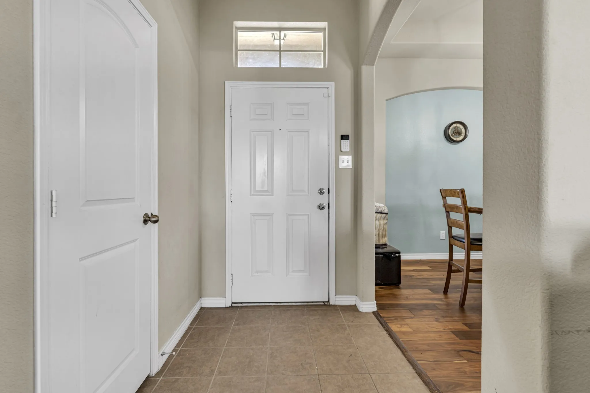 Entryway featuring durable tile flooring, a transom window, and a paneled entry door