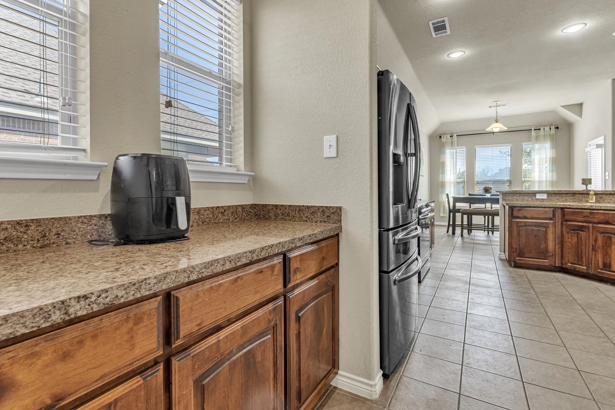 Kitchen featuring wood cabinetry, stone-finish countertops, stainless steel refrigerator, and recessed lighting