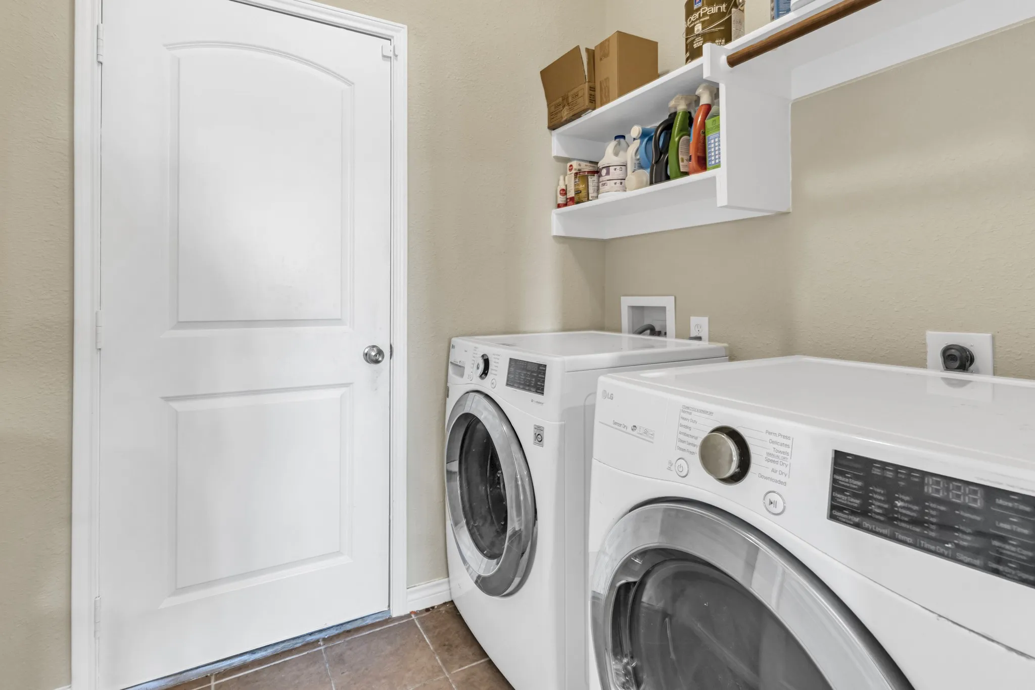 Laundry area with tile flooring, built-in shelving, and a hanging rod