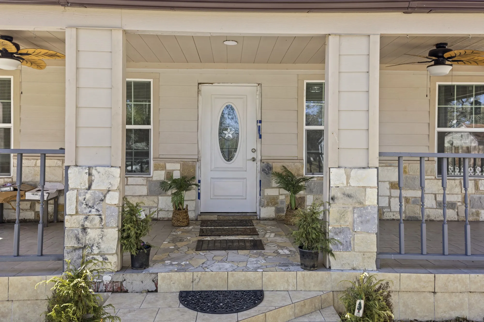 Property entrance with ceiling fan, stone siding, and covered porch