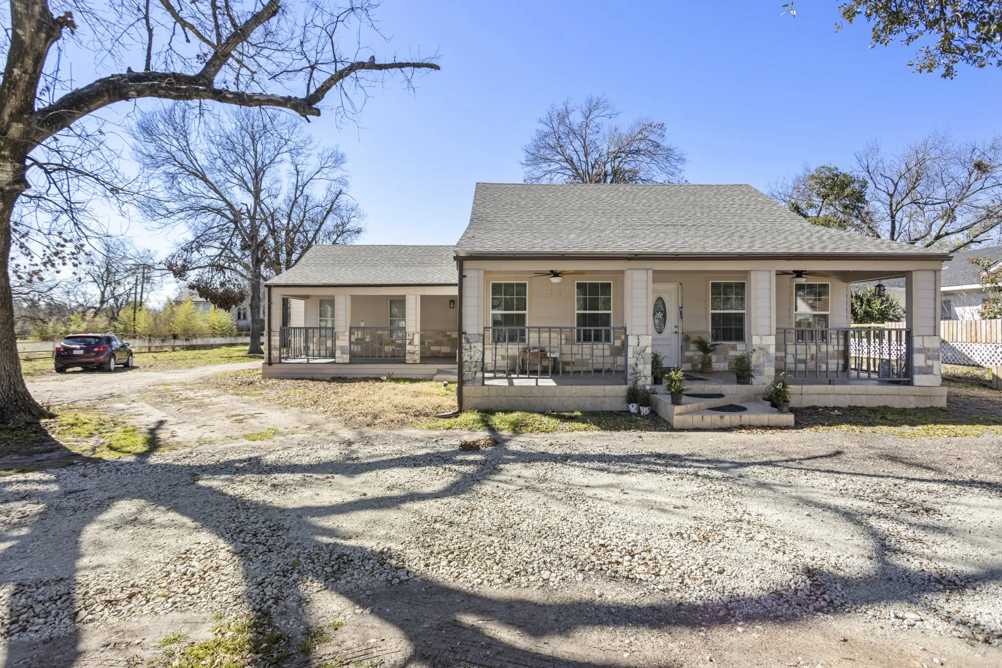 Rear view of property featuring covered porch, a ceiling fan, roof with shingles, and driveway